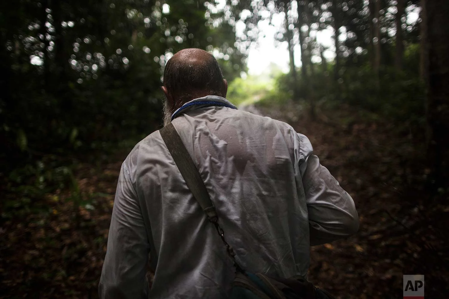 In this Jan. 15, 2018 photo, Father Pablo Zabala, better known as Padre Pablo, makes his way through the jungle under a heavy rain to the rural home of a parishioner in Boca Colorado, part of Peru’s Madre de Dios region in the Amazon. (AP Photo/Rodrigo Abd) | See these photos on AP Images