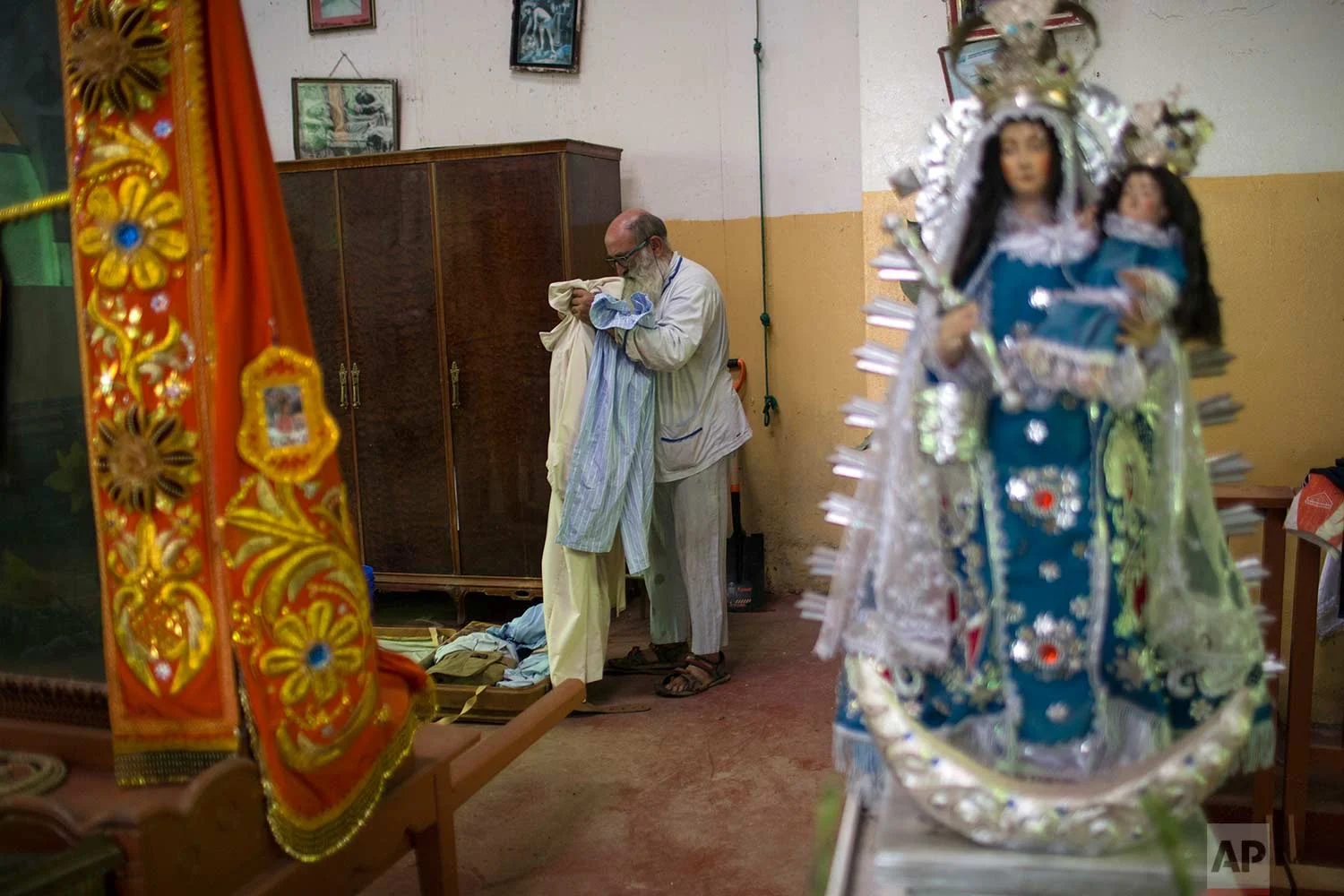 In this Jan. 14, 2018 photo, Pablo Zabala, better known as Padre Pablo, packs his more than 30 pairs of pajamas into a suitcase in the sacristy of the Senor de Qoyllority Catholic Church, in Puerto Carlos, part of Peru’s Madre de Dios province in the Amazon. The 70-year-old Spanish priest credits women who labor as sex workers in nearby bars with helping build two churches and has encouraged them to pray to Mary Magdalene. Each year he takes a sculpture of the woman considered Jesus’ most important female disciple into a local bar as part of a religious procession. (AP Photo/Rodrigo Abd) | See these photos on AP Images