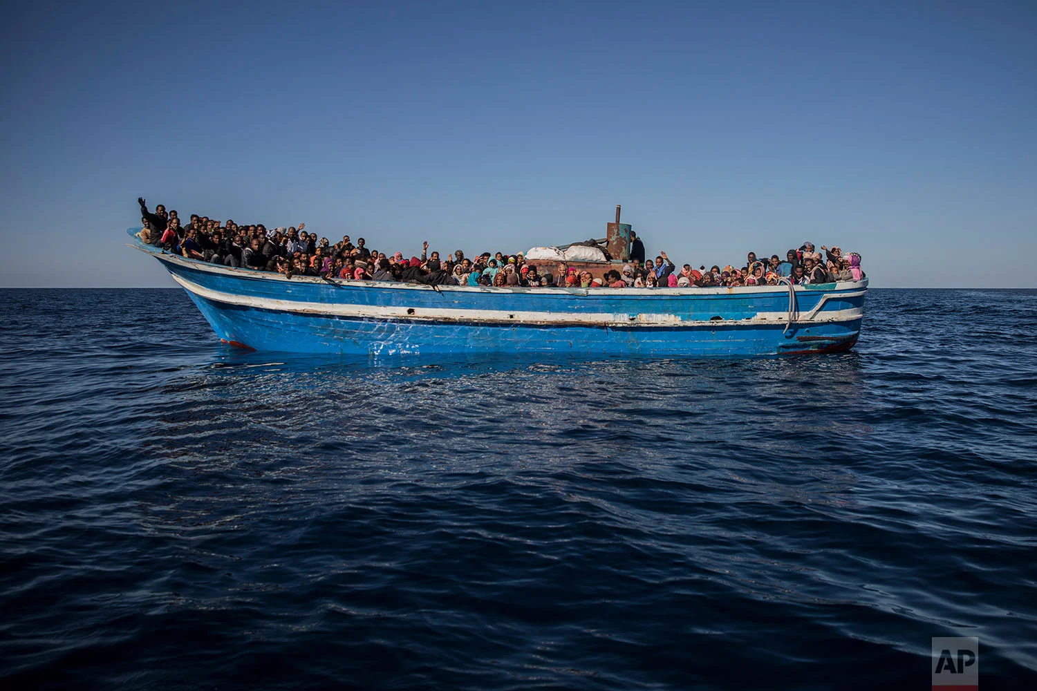 In this Tuesday, Jan. 16, 2018, photo, about 450 Sub-Saharan refugees and migrants, mostly from Eritrea, wait to be rescued by aid workers of Spanish NGO Proactiva Open Arms, as they were trying to leave the Libyan coast and reach European soil aboard an overcrowded wooden boat, 34 miles north of Kasr-El-Karabulli, Libya. (AP Photo/Santi Palacios) 