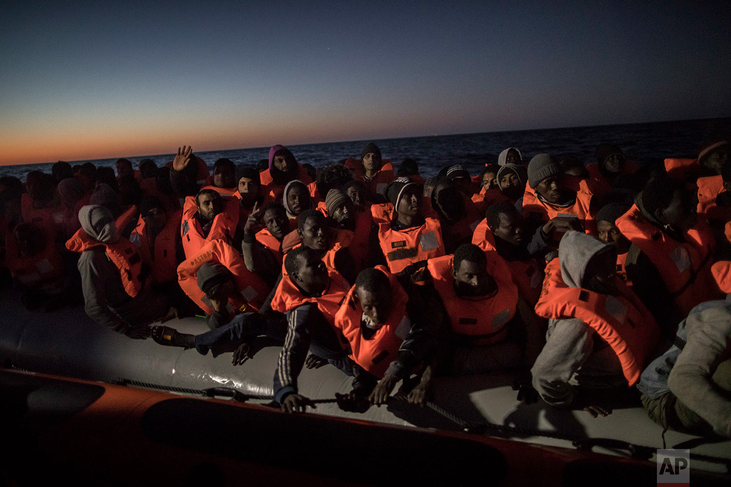  In this Tuesday, Jan. 16, 2018, photo, Sub-Saharan refugees and migrants from different nationalities trying to leave the Libyan coast and reach European soil aboard an overcrowded rubber boat are rescued by a team of aid workers from the Spanish NG