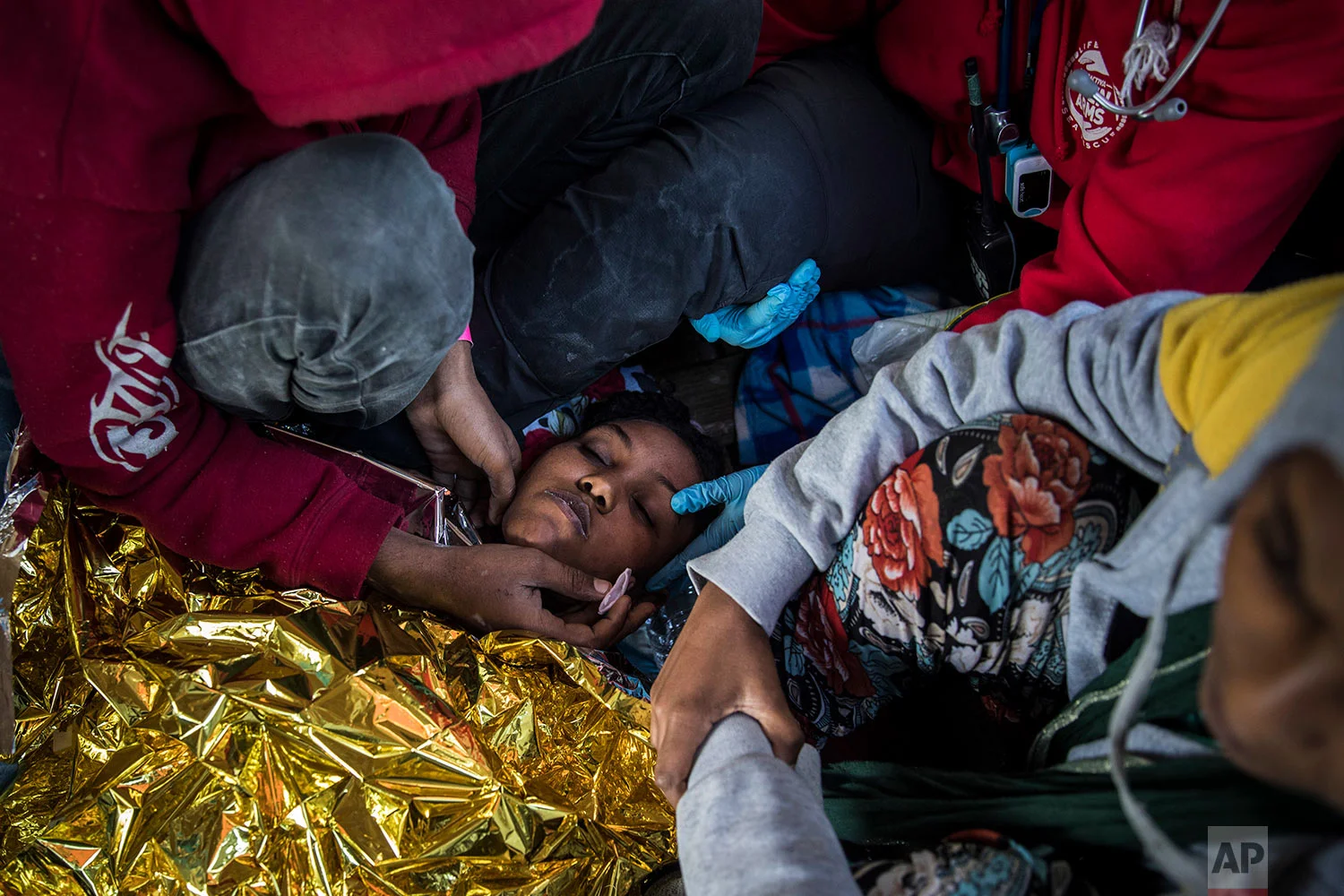 In this Thursday, Jan. 18, 2018 photo a doctor from the Spanish NGO Proactiva Open Arms assists an Eritrean woman as the organization's rescue vessel heads to Italy with more than 300 refugees and migrants on board. (AP Photo/Santi Palacios) 