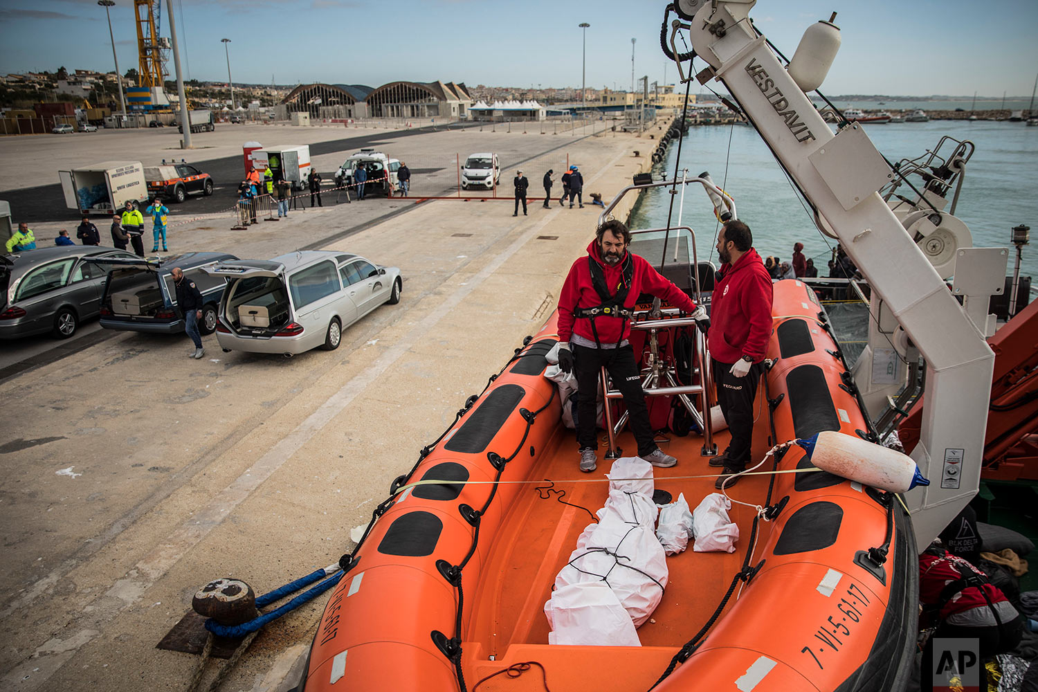  In this Friday, Jan. 19, 2018 photo aid workers from the Spanish NGO Proactiva Open Arms wait to disembark the lifeless bodies of an Eritrean man and 2 babies from the organization's rescue vessel, at the port of Pozzallo, in Sicily, Italy. (AP Phot