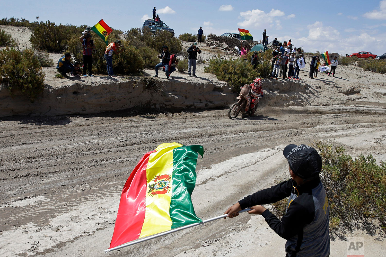  In this Saturday, Jan. 13, 2018 photo, spectators wave Bolivian flags as France's Gasgas motorbike rider Johnny Aubert races during stage 7 of the Dakar Rally between La Paz and Uyuni, Bolivia. (AP Photo/Ricardo Mazalan) |&nbsp; See these photos on 