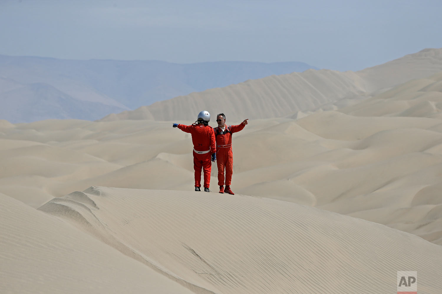  In this Wednesday, Jan. 10, 2018 photo, Philippe Raud, of France, right, and Miguel Angel Alvarez Pineda, of Peru, both drivers of Toyota cars, point in opposite directions as they try to determine their way across the dunes during stage 5 of the Da