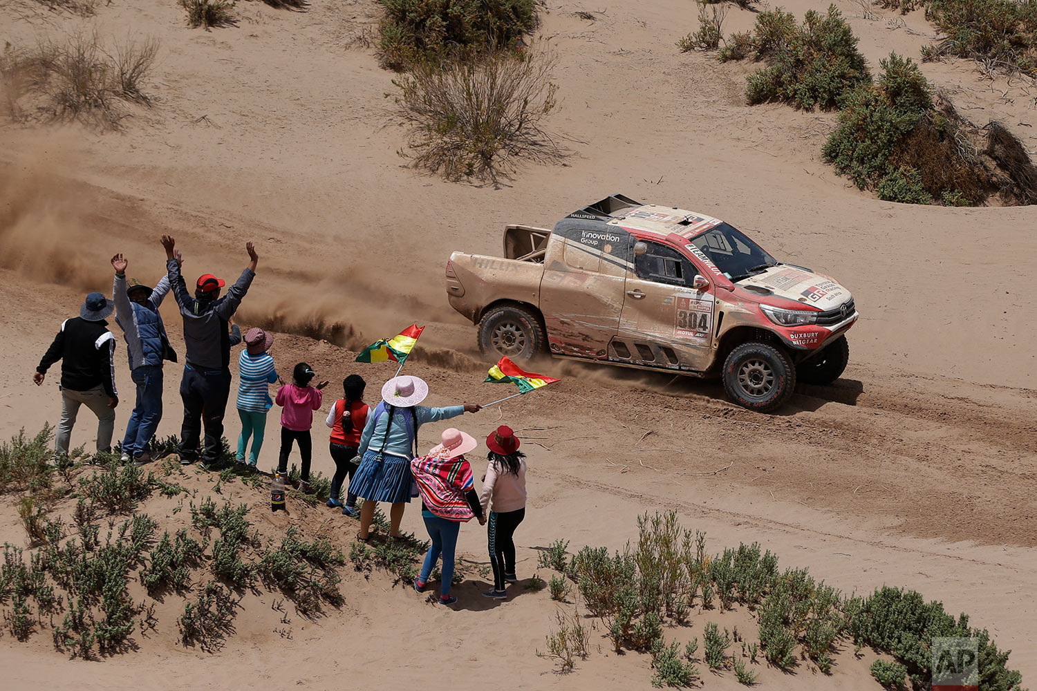  In this Sunday, Jan. 14, 2018 photo, spectators cheer as Driver Giniel De Villiers, of South Africa, and co-driver Dirk Von Zitzewitz, of Germany, race their Toyota during the 8th stage of the Dakar Rally between Uyuni and Tupiza, Bolivia. De Villie