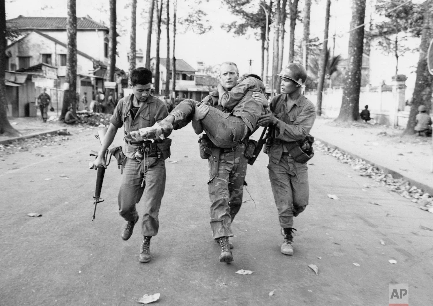 In this Feb. 6, 1968 photo, First Lt. Gary D. Jackson of Dayton, Ohio, carries a wounded South Vietnamese Ranger to an ambulance after a brief but intense battle with the Viet Cong during the Tet Offensive near the National Sports Stadium in the Cholon section of Saigon. Early on the morning of Jan. 31, 1968, as Vietnamese celebrated the Lunar New Year, or Tet as it is known locally, Communist forces launched a wave of coordinated surprise attacks across South Vietnam. The campaign, one of the largest of the Vietnam War, led to intense fighting and heavy casualties in cities and towns across the South. (AP Photo/Dang Van Phuoc)