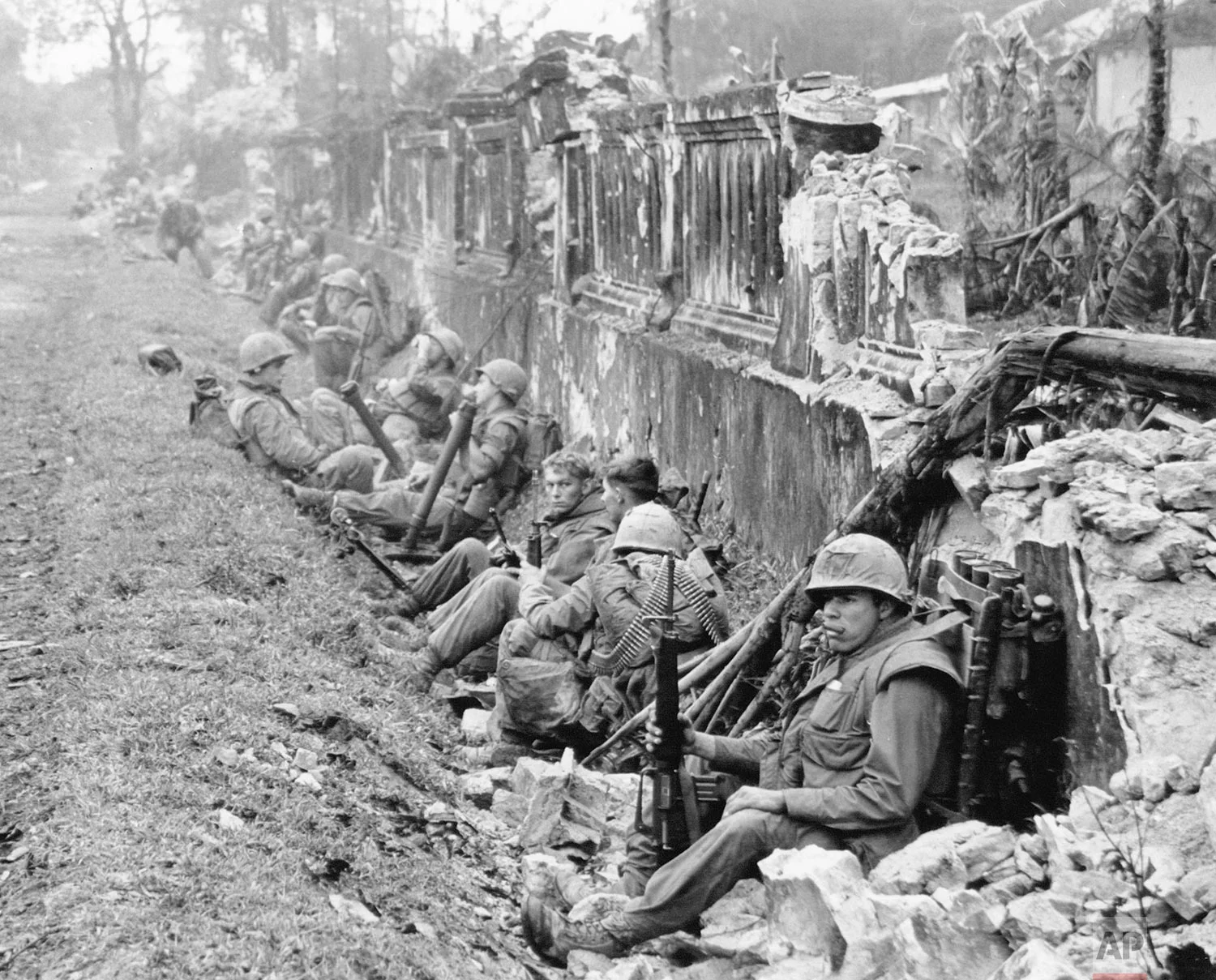 In this Feb. 1968 photo, a unit of the 1st Battalion, 5th Regiment U.S. Marines, rests alongside a battered wall of Hue's imperial palace after a battle for the Citadel during the Tet Offensive. The Marines reported heavy casualties in street fighting in the ancient capital city of Vietnam. Early on the morning of Jan. 31, 1968, as Vietnamese celebrated the Lunar New Year, or Tet as it is known locally, Communist forces launched a wave of coordinated surprise attacks across South Vietnam. The campaign, one of the largest of the Vietnam War, led to intense fighting and heavy casualties in cities and towns across the South. (AP Photo)