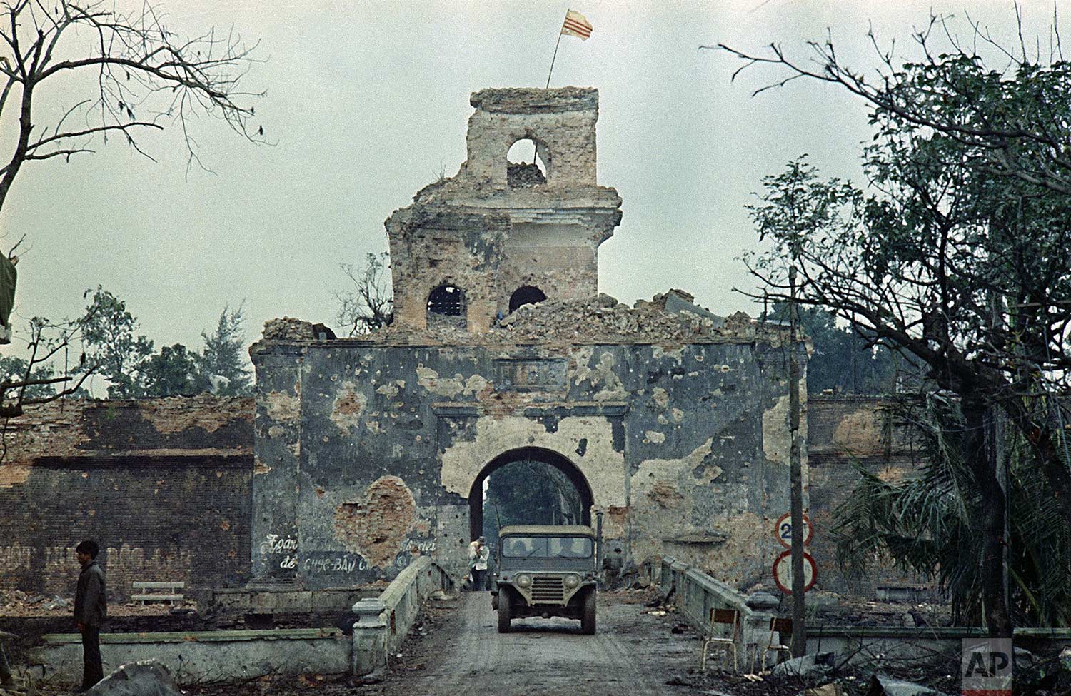  The Vietnam flag flies atop a tower of the main fortified structure in the old citadel as a jeep crosses a bridge over a moat in Hue, during the Tet Offensive, Feb. 1968.  (AP Photo) 