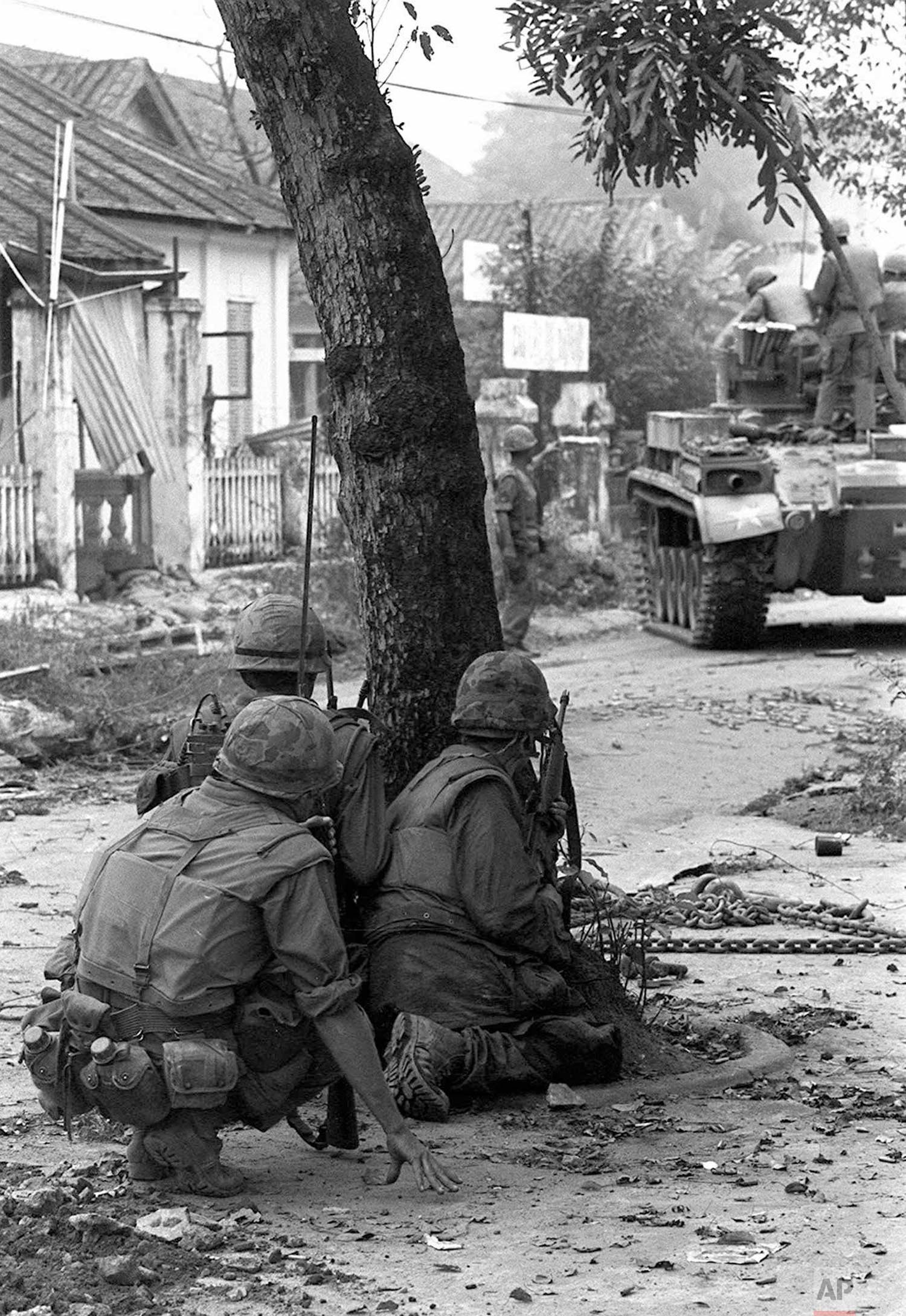 U.S. Marines, supplemented by a tank, take cover behind a tree near the southern bridgehead on the Perfume River, in Hue, Vietnam, Feb. 4, 1968 as they fight well-armed North Vietnamese troops for the fifth straight day. The communists continued to