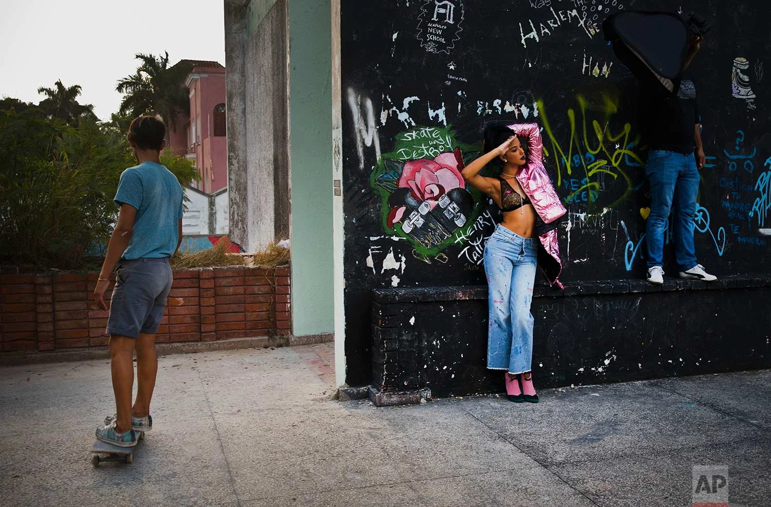 In this Jan. 11, 2018 photo, a young model and a member of the lighting crew use as their backdrop an abandoned gym that was converted into space for skateboarders, the day of the space's inauguration inside the Educational complex Ciudad Libertad, a former military barracks that the late Fidel Castro turned into a school complex after the revolution in Havana, Cuba. (AP Photo/Ramon Espinosa)