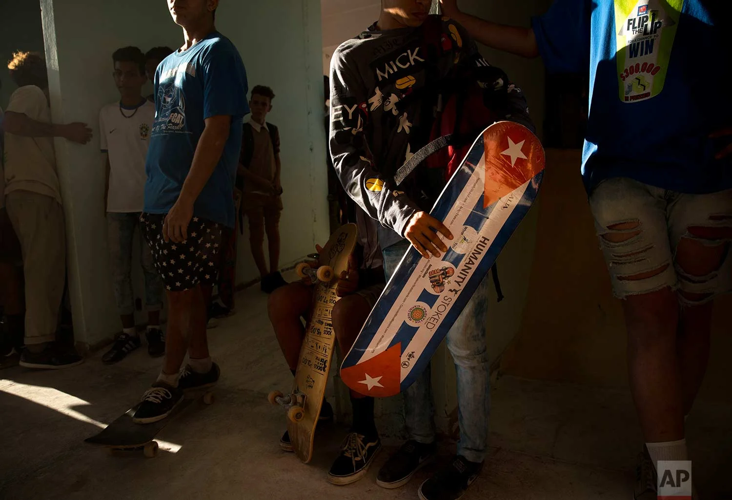 In this Jan. 11, 2018 photo, a skater carries a new Cuban flag motiffed skateboard, donated by Humanity Stoked, during the inauguration of a new recreational space for skateboarders, created out of an abandoned gym at the Educational complex Ciudad Libertad, a former military barracks that the late Fidel Castro turned into a school complex after the revolution in Havana, Cuba. (AP Photo/Ramon Espinosa)