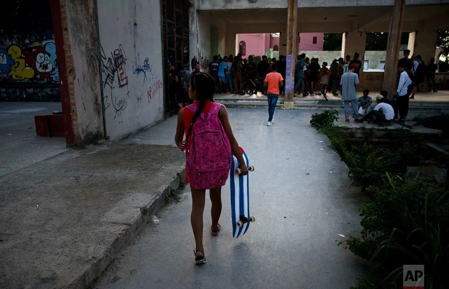 In this Jan. 11, 2018 photo, a young girl carries her Cuba flag motif skateboard to the inauguration ceremony of a new recreational space for skateboarders, created in an abandoned gym at the Educational complex Ciudad Libertad, a former military barracks that the late Fidel Castro turned into a school complex after the revolution in Havana, Cuba. (AP Photo/Ramon Espinosa)