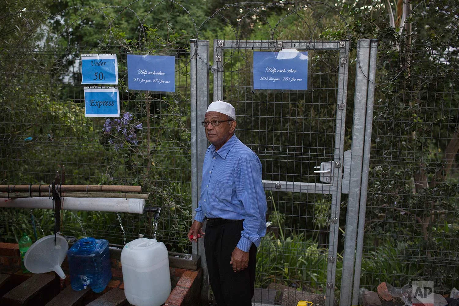 A man collects water from a source of natural spring water in Cape Town, Thursday, Feb. 1, 2018. (AP Photo/Bram Janssen)