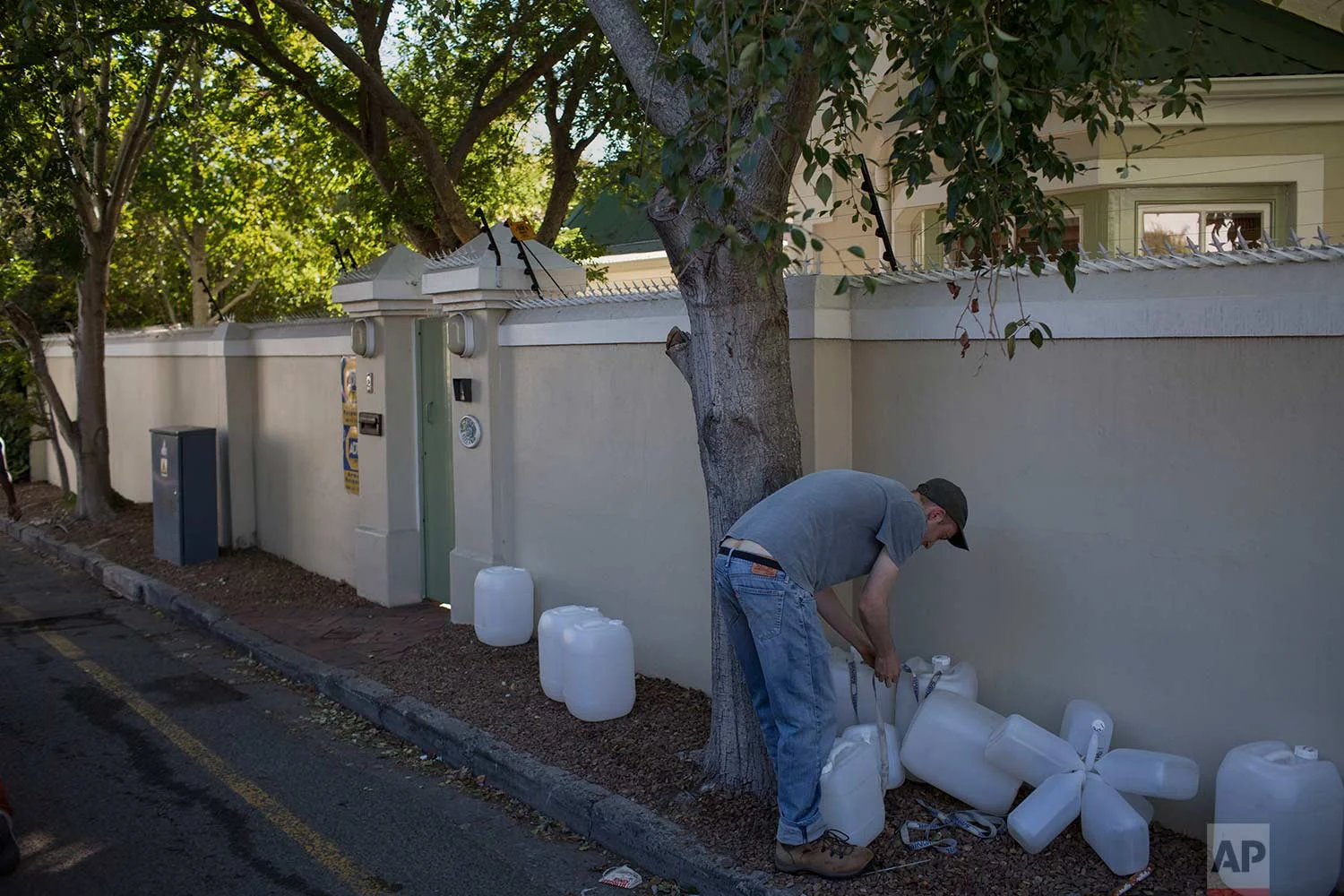A Cape Town resident sorts out his containers as he arrives at a source of natural spring water in the city on Thursday, Feb. 1, 2018. (AP Photo/Bram Janssen)