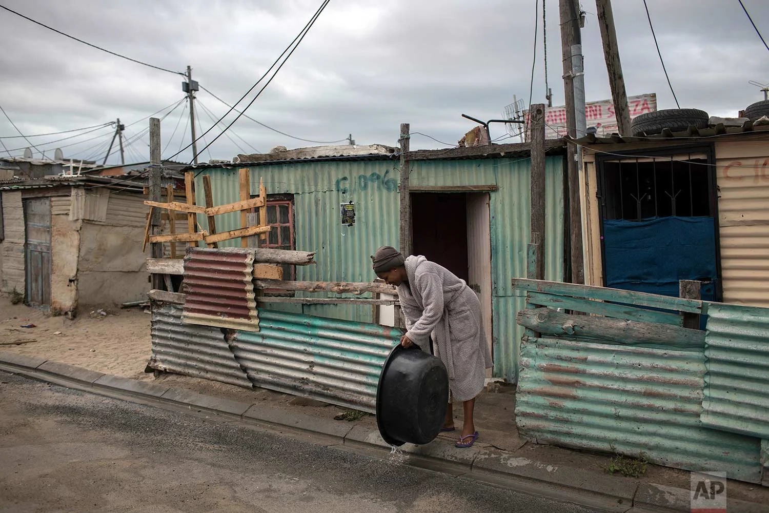 A woman throws away used water in a settlement near Cape Town on Friday, Feb. 2, 2018. (AP Photo/Bram Janssen)