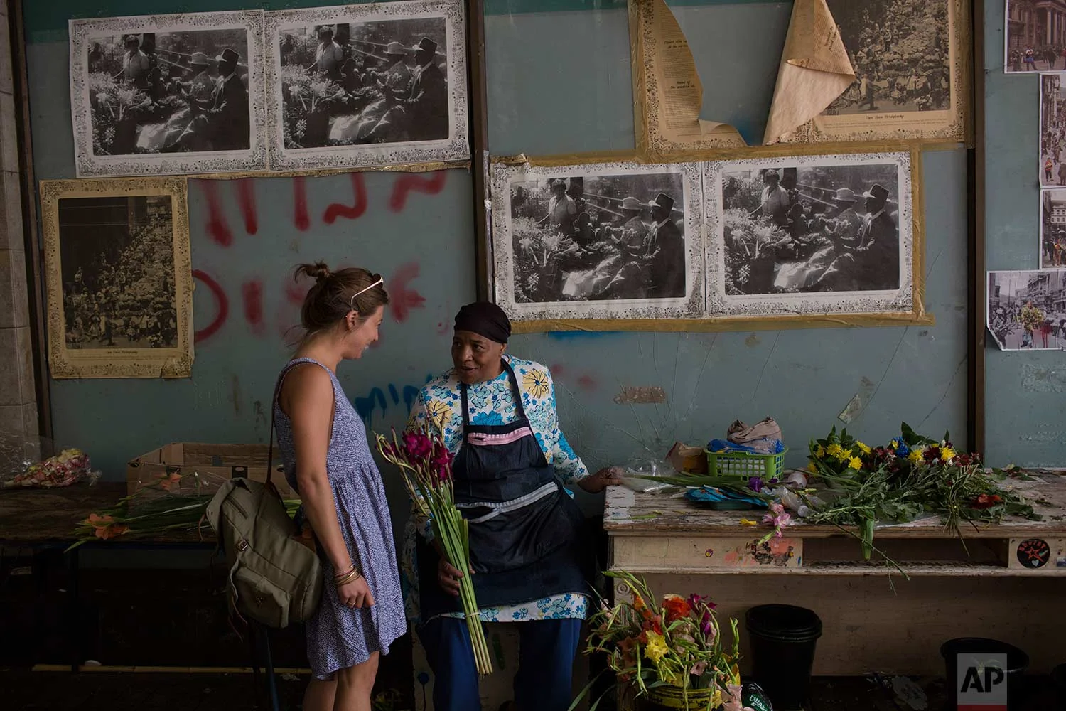 In this Thursday, Feb. 1, 2018, Faldela Dixon talks to a customer at her flower shop in Cape Town. Dixon says customers don't buy as many flowers because of the drought, as they don't want to waste water to water the flowers. (AP Photo/Bram Janssen)
