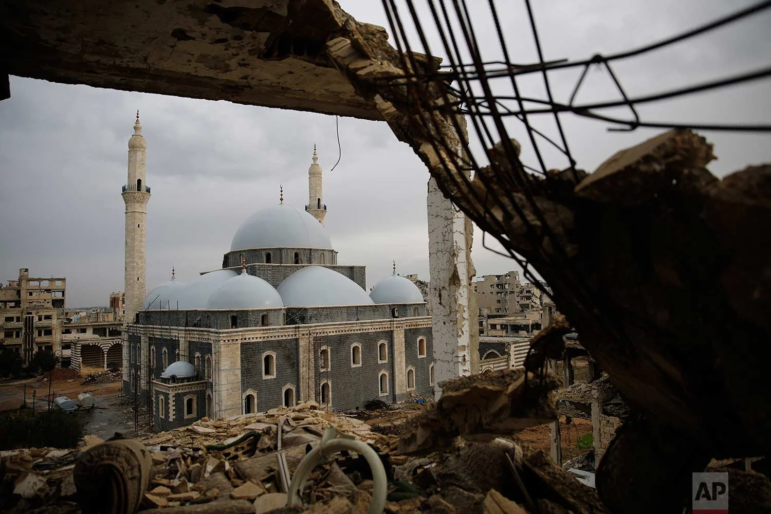 The reconstructed Khaled Bin al-Waleed Mosque is framed by a damaged building, in the old city of Homs, Syria, Wednesday, Jan. 17, 2018. (AP Photo/Hassan Ammar)