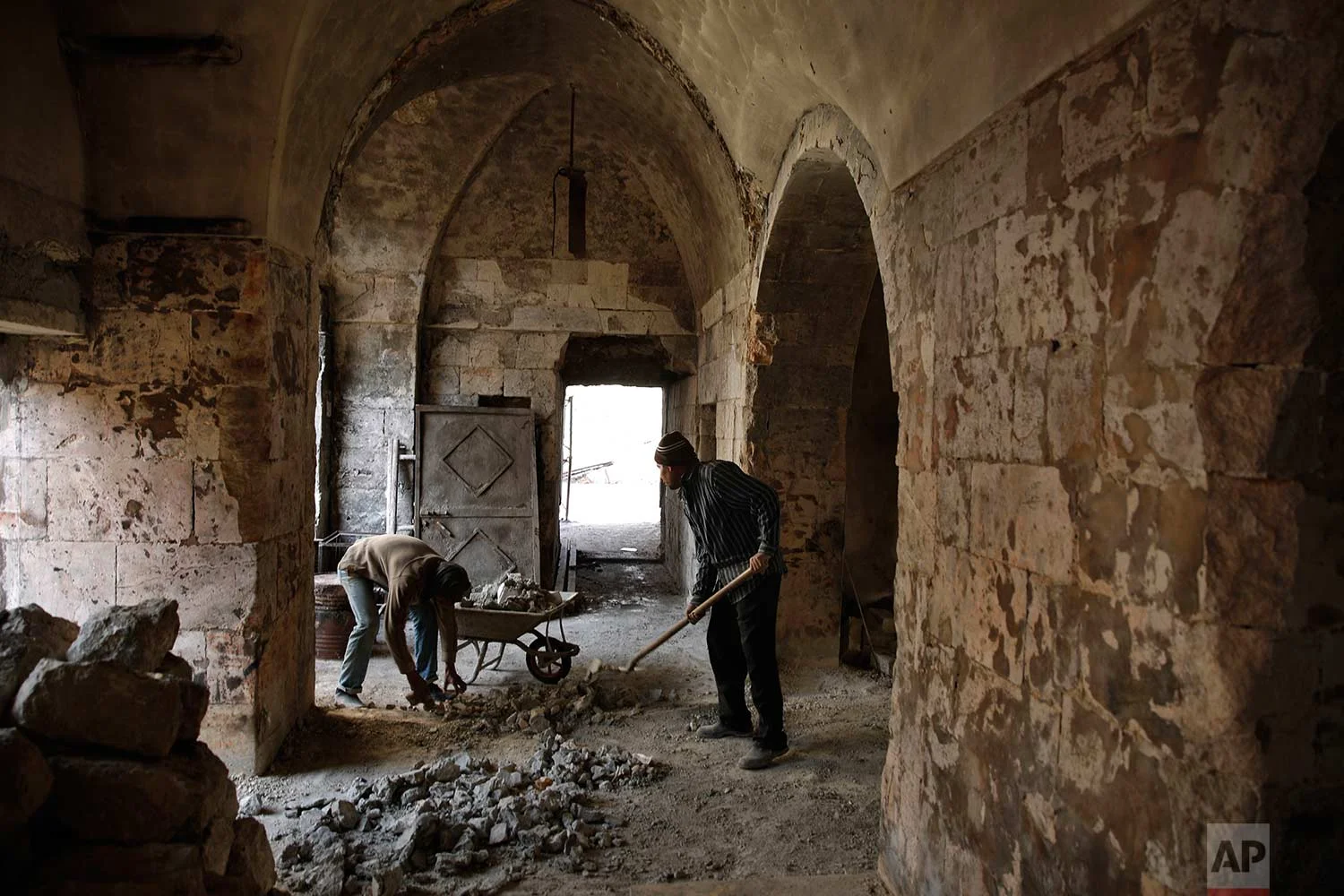 Syrian men remove rubble from a damaged shop at the old market in the old city of Aleppo, Syria on Jan. 18, 2018. (AP Photo/Hassan Ammar)
