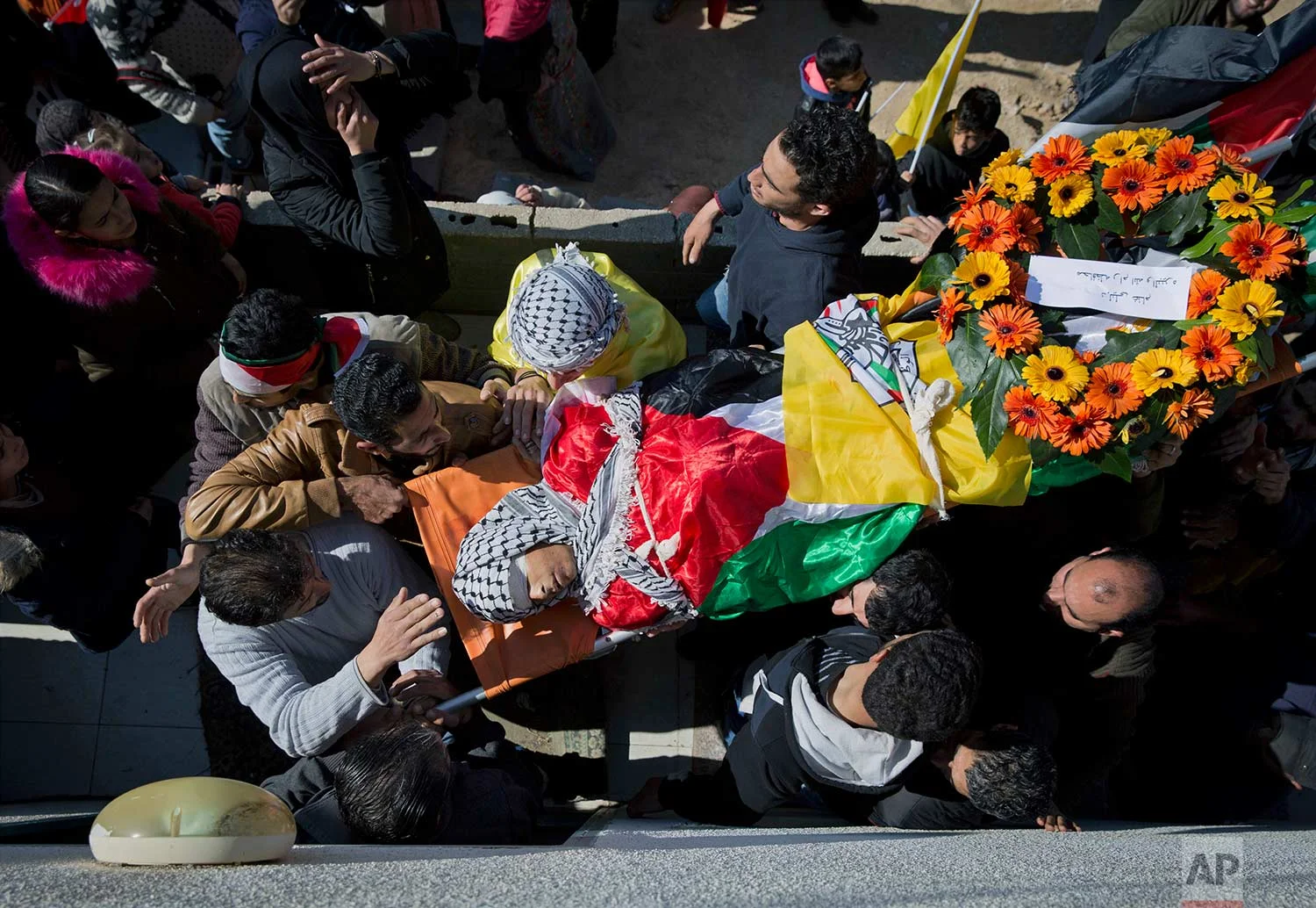 Palestinian mourners carry the body of Laith Abu Naim, into the family house during his funeral in the West Bank village of Mughayer, north of Ramallah, Wednesday, Jan. 31, 2018. The 16-year-old Palestinian was shot and killed in clashes between the Israeli military and stone throwers in the West Bank village Tuesday, Palestinian officials said. The Israeli military denied using live fire amid a "violent riot" in which dozens of Palestinians rolled burning tires and hurled rocks at troops. (AP Photo/Nasser Nasser)