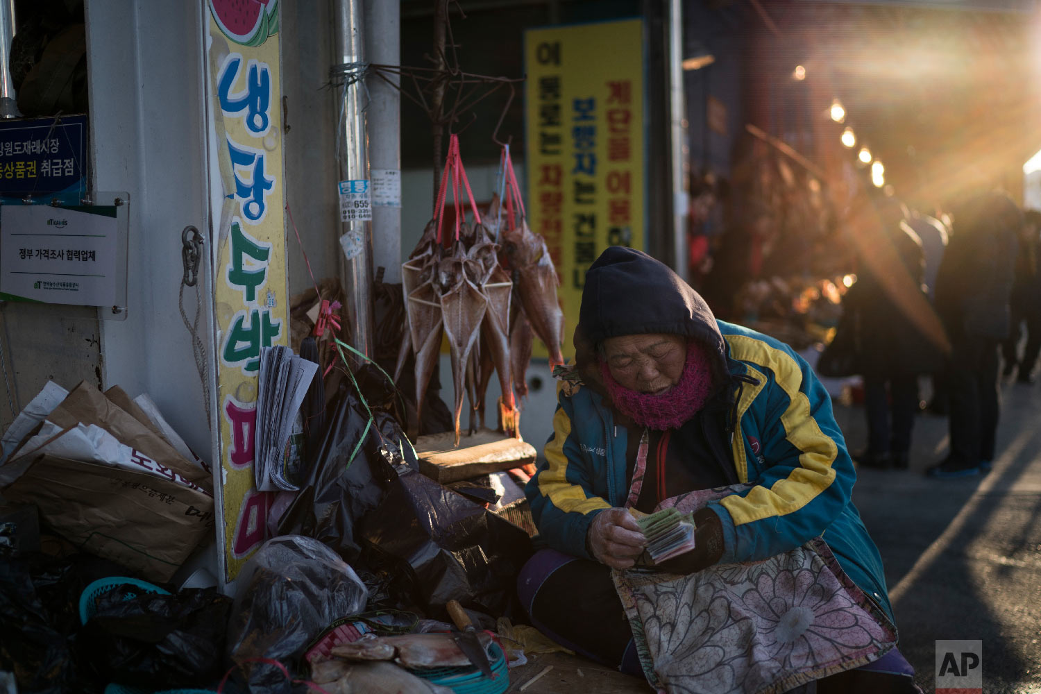 A woman selling fish waits for customers at a market in Gangneung, South Korea, Monday, Feb. 12, 2018. One part of the Pyeongchang area that hasn’t been Westernized and beautified for the Winter Olympics is the traditional market in Gangneung, several blocks of street stalls operated for the most part by old women who are decidedly no-nonsense about selling their wares - from naturally dried octopus legs to goopy globs of seaweed freshly harvested from the local waters. (AP Photo/Felipe Dana)