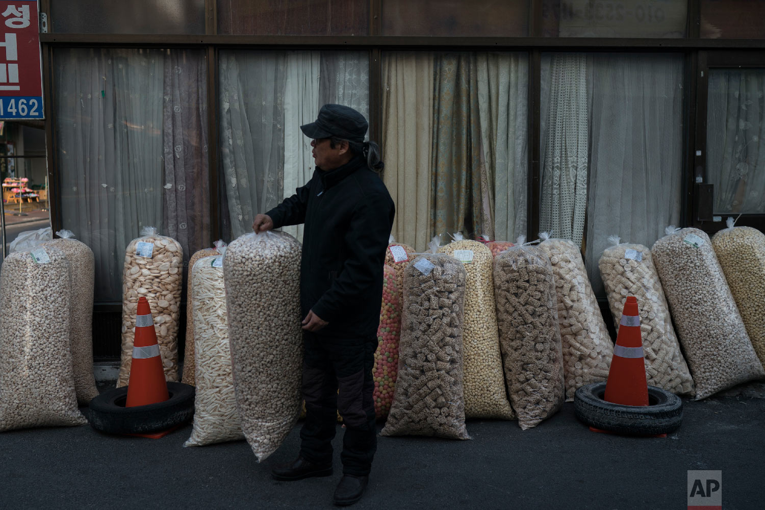 A man sells large bags of popped grains at the traditional market in Gangneung, South Korea, Tuesday, Feb. 13, 2018. Markets like this one are a common sight in South Korea. And while the Pyeongchang promoters are hoping it will impress the foreign tourists here for the games, it hasn’t been given much of an Olympic makeover. (AP Photo/Felipe Dana)