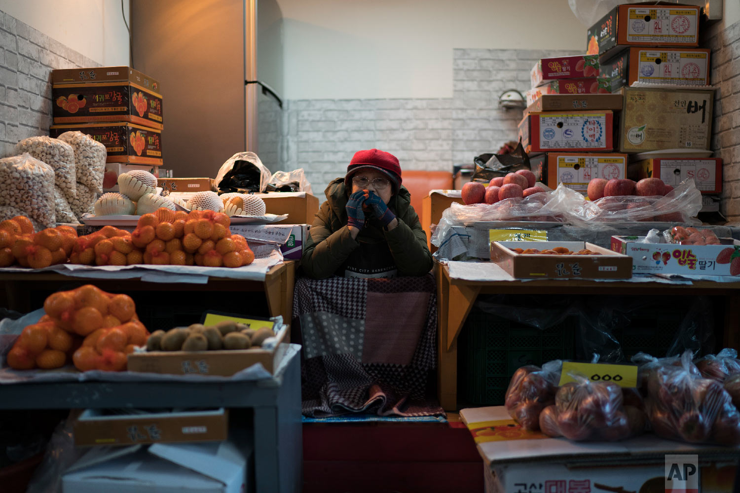 A woman selling fruits waits for costumers at the traditional market in Gangneung, South Korea, Monday, Feb. 12, 2018. One part of the Pyeongchang area that hasn’t been Westernized and beautified for the Winter Olympics is the traditional market in Gangneung, several blocks of street stalls operated for the most part by old women who are decidedly no-nonsense about selling their wares (AP Photo/Felipe Dana)