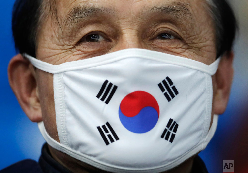  A spectators wears a protective mask with the South Korean flag as he waits for the start of the men's 10,000 meters speedskating race at the Gangneung Oval at the 2018 Winter Olympics in Gangneung, South Korea, Thursday, Feb. 15, 2018. (AP Photo/Pe