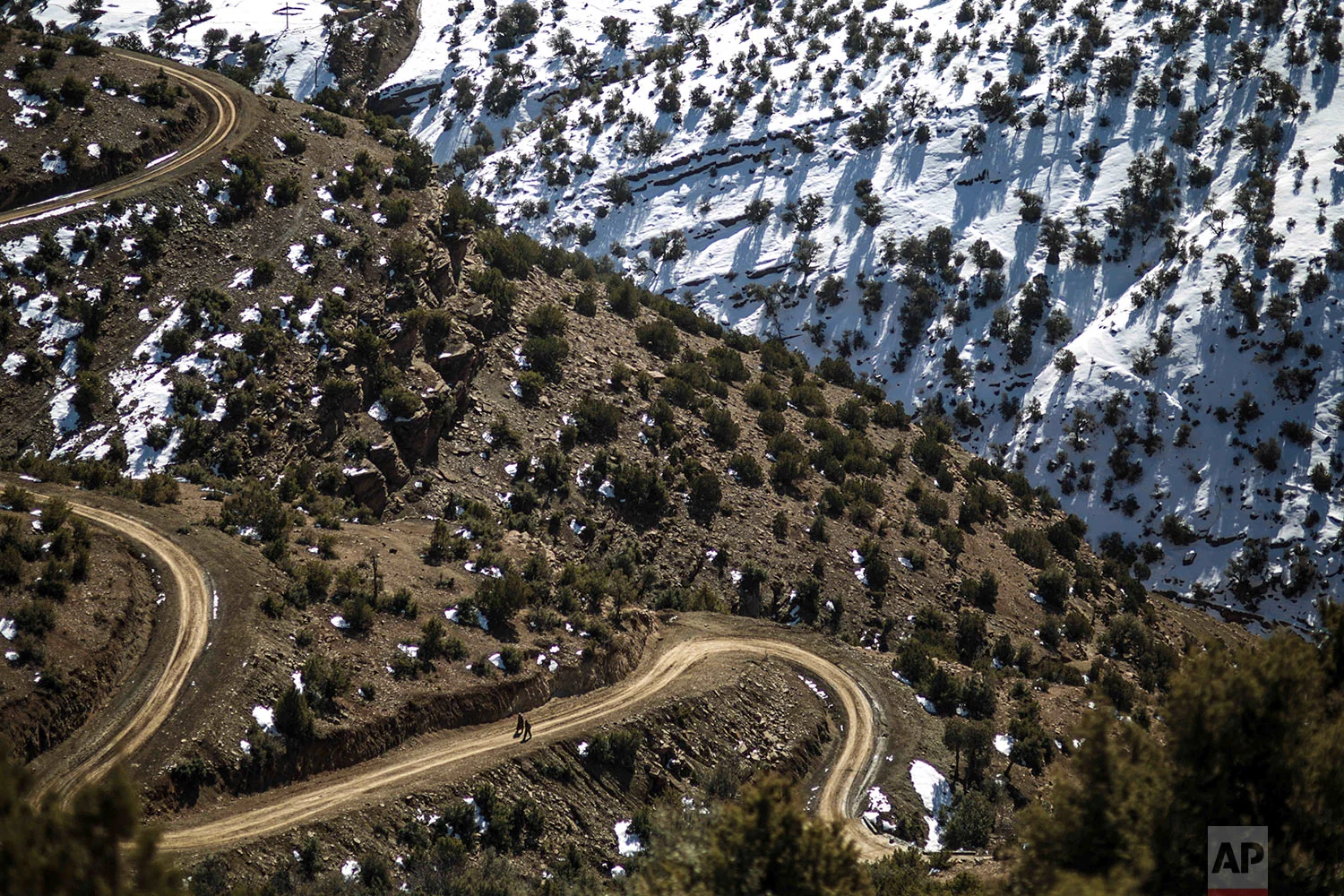 In this Wednesday, Feb. 14, 2018 photo, villagers walk through a slope on their way to Tighanmin, a Middle Atlas village near Azilal, central Morocco. (AP Photo/Mosa'ab Elshamy)