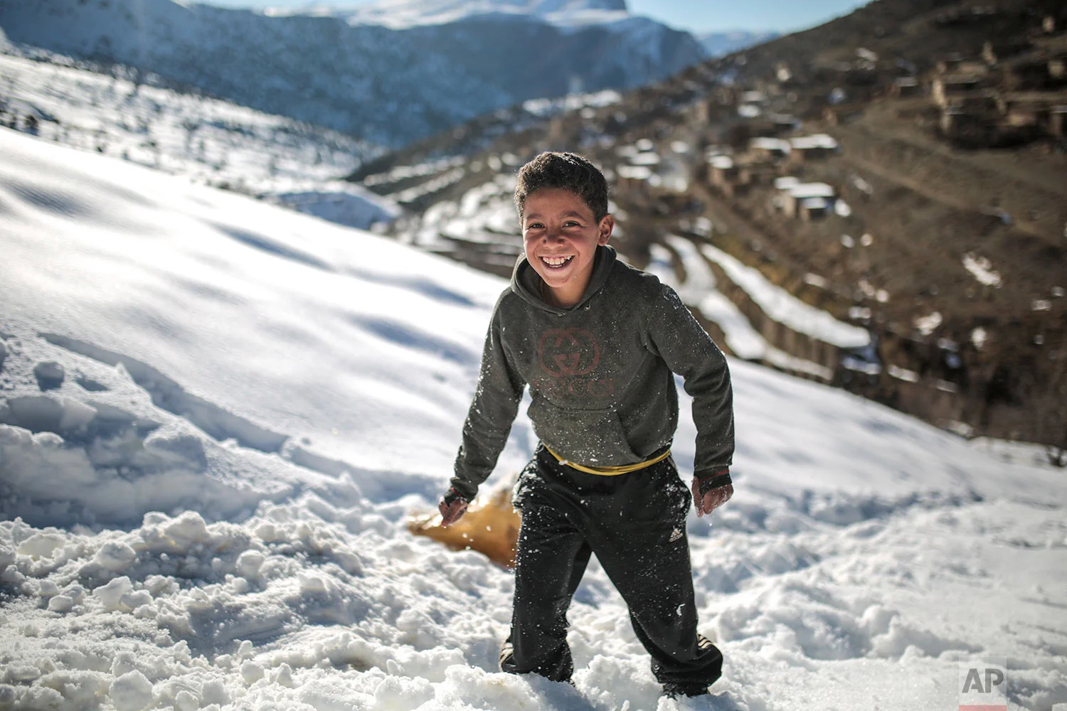 In this Wednesday, Feb. 14, 2018 photo, Mouhcine, 11, enjoys sledging on snow covered mountains in Tighanmin, a Middle Atlas village near Azilal, central Morocco. (AP Photo/Mosa'ab Elshamy)