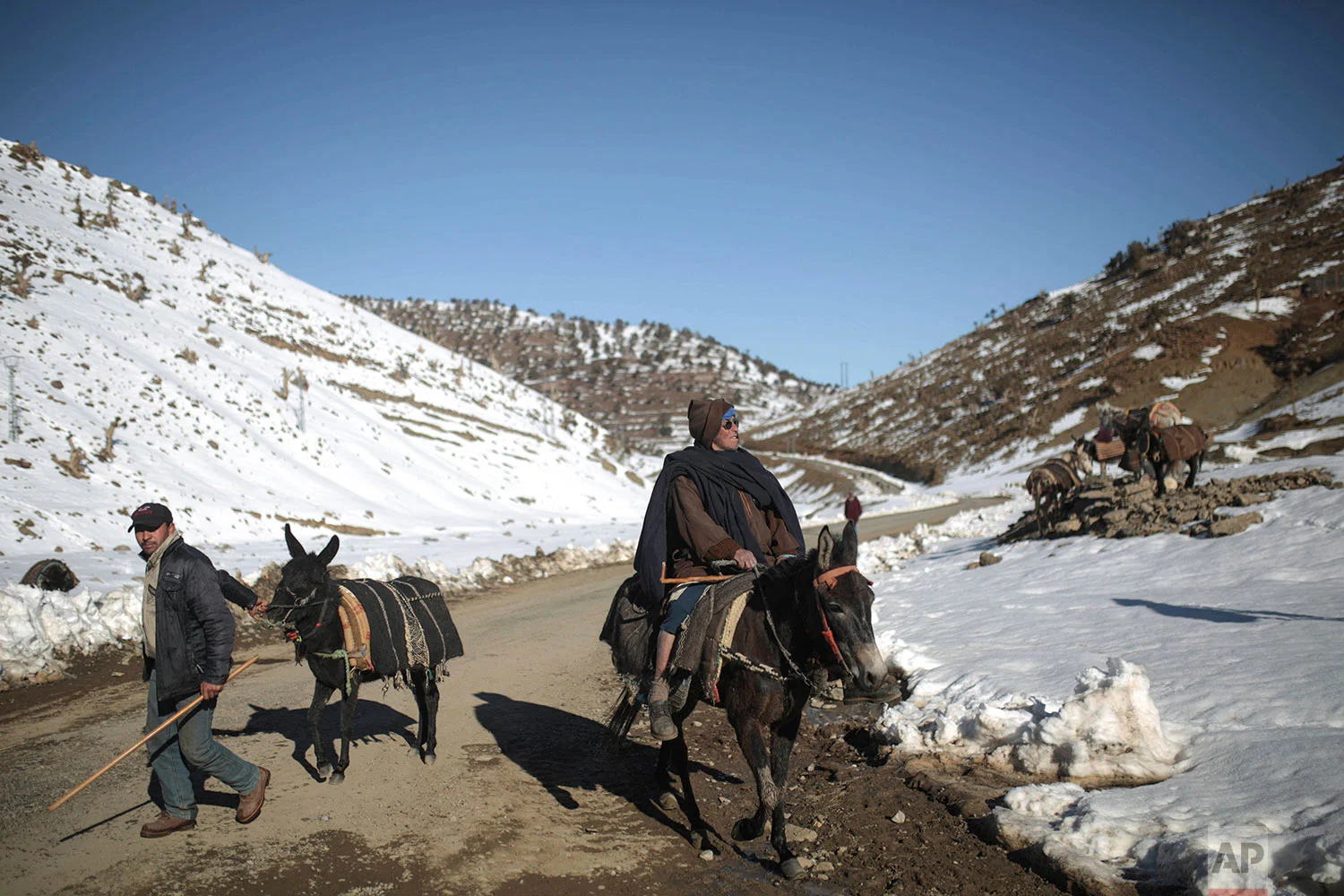 In this Thursday, Feb. 15, 2018 photo, Berber villagers ride their donkeys through snow covered mountains in Tighanmin, a Middle Atlas village near Azilal, central Morocco. (AP Photo/Mosa'ab Elshamy)