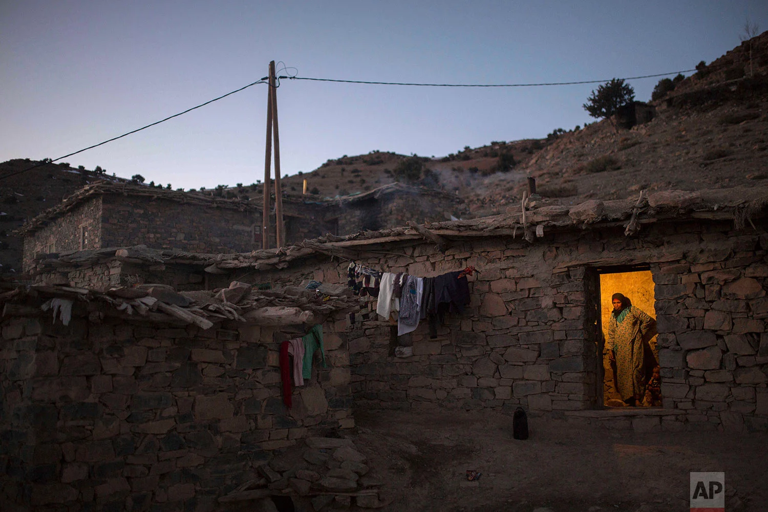 In this Wednesday, Feb. 14, 2018 photo, a woman waits for her family as she prepares dinner in Tighanmin, a Middle Atlas village near Azilal, central Morocco. (AP Photo/Mosa'ab Elshamy)
