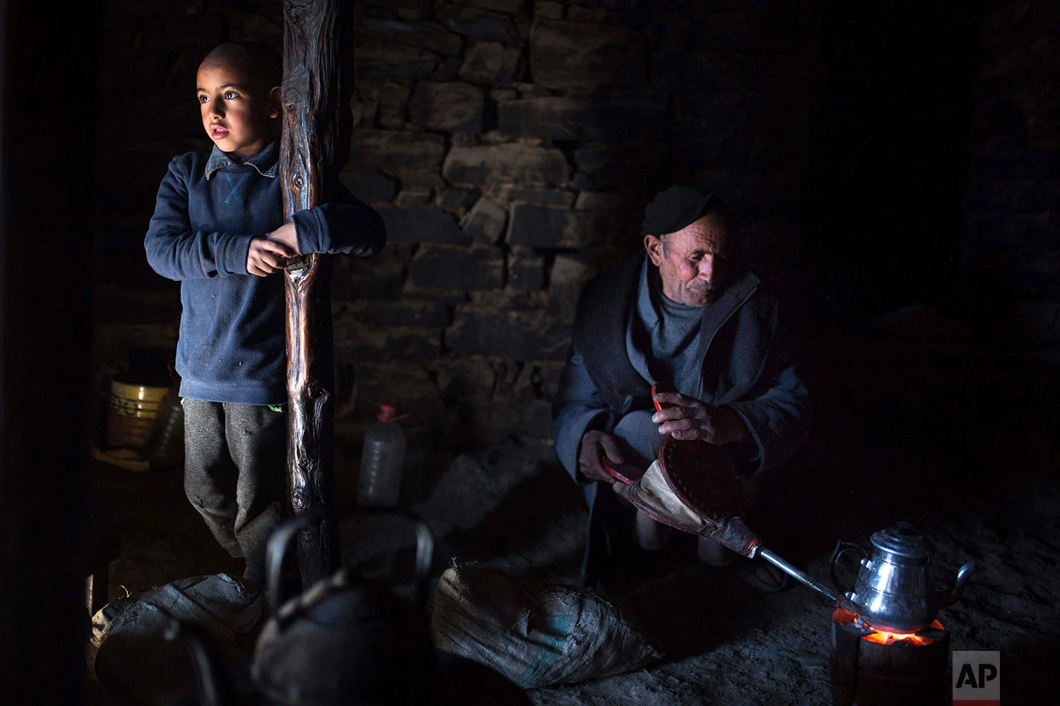 In this Wednesday, Feb. 14, 2018 photo, Mostfa Oulhassan, 68, prepares tea for his family inside his home in Tighanmin, a Middle Atlas village near Azilal, central Morocco. (AP Photo/Mosa'ab Elshamy)