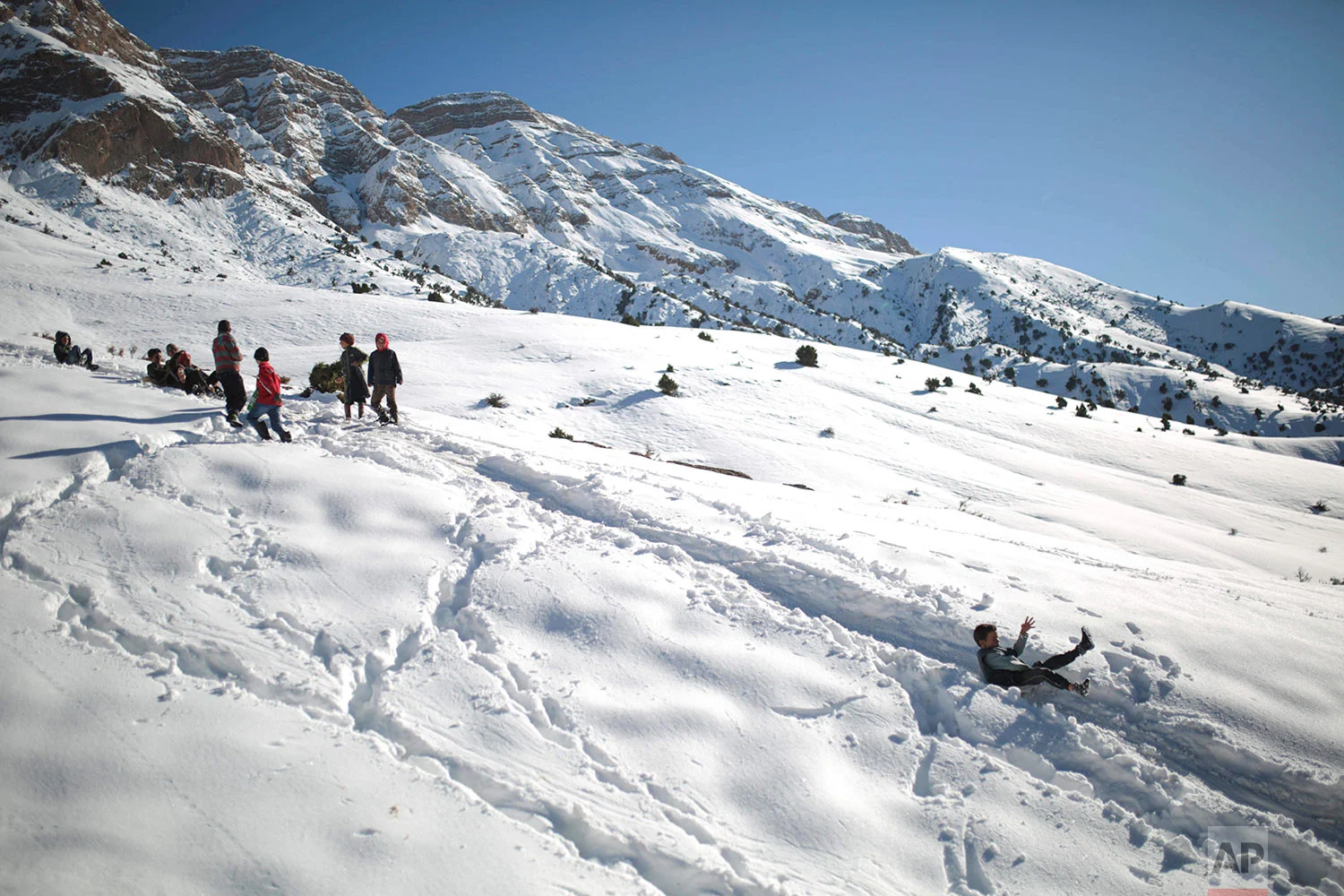 In this Wednesday, Feb. 14, 2018 photo, children enjoy sledging after school on snow covered mountains in Tighanmin, a Middle Atlas village near Azilal, central Morocco. (AP Photo/Mosa'ab Elshamy)