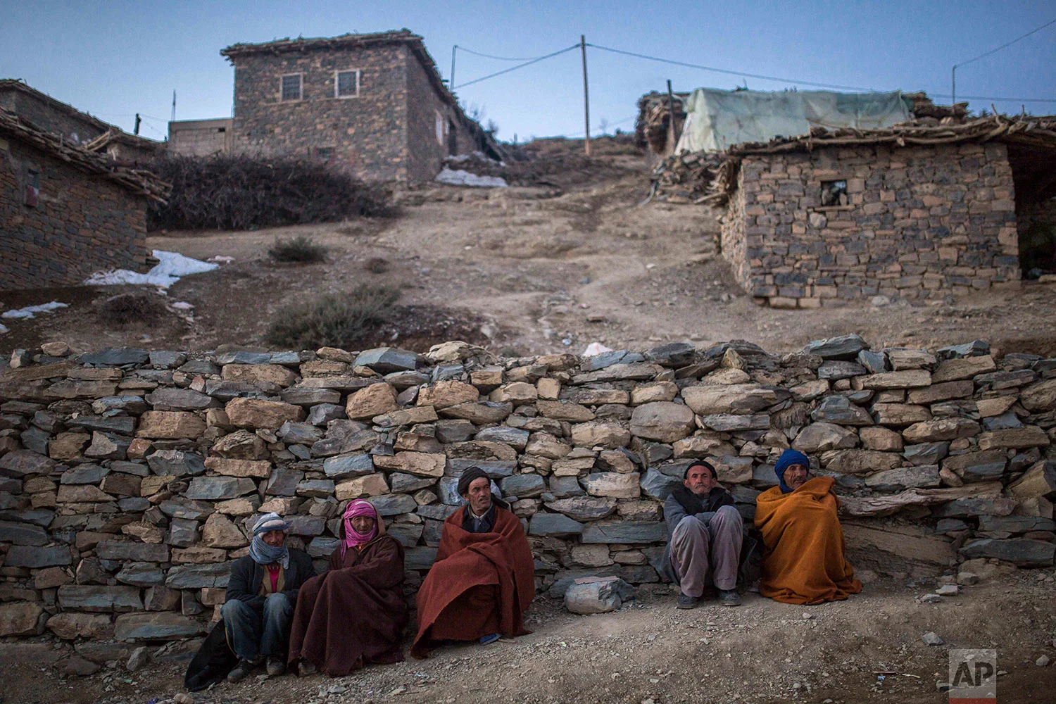 In this Wednesday, Feb. 14, 2018 photo, Berber villagers gather for warmth in the evening sun in Tighanmin, a Middle Atlas village near Azilal, central Morocco. (AP Photo/Mosa'ab Elshamy)
