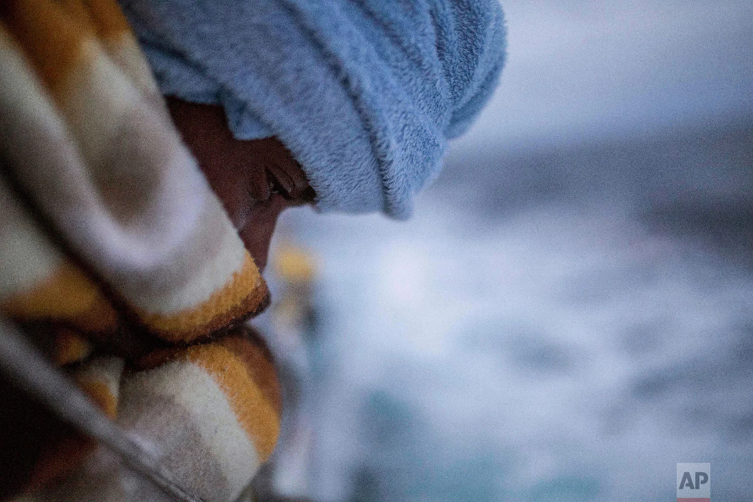 In this photo taken on Sunday Feb. 18, 2018 photo, a man stands on the deck after being rescued by aid workers of the Spanish NGO Proactiva Open Arms, after leaving Libya trying to reach European soil aboard an overcrowded rubber boat, 60 miles nort