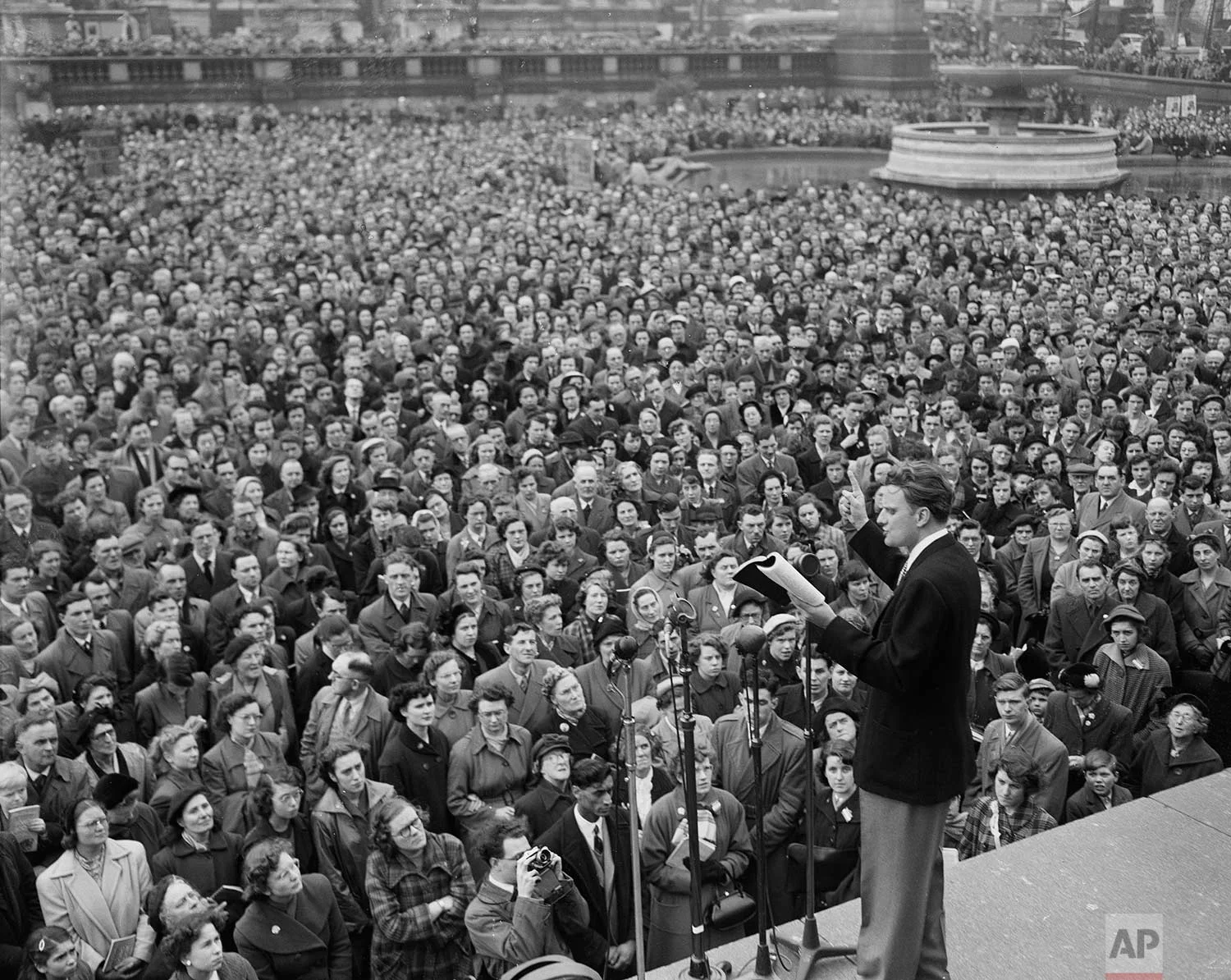 American evangelist Billy Graham reads passages from the Bible to a large, rapt audience in Trafalgar Square, London, April 12, 1954. (AP Photo)