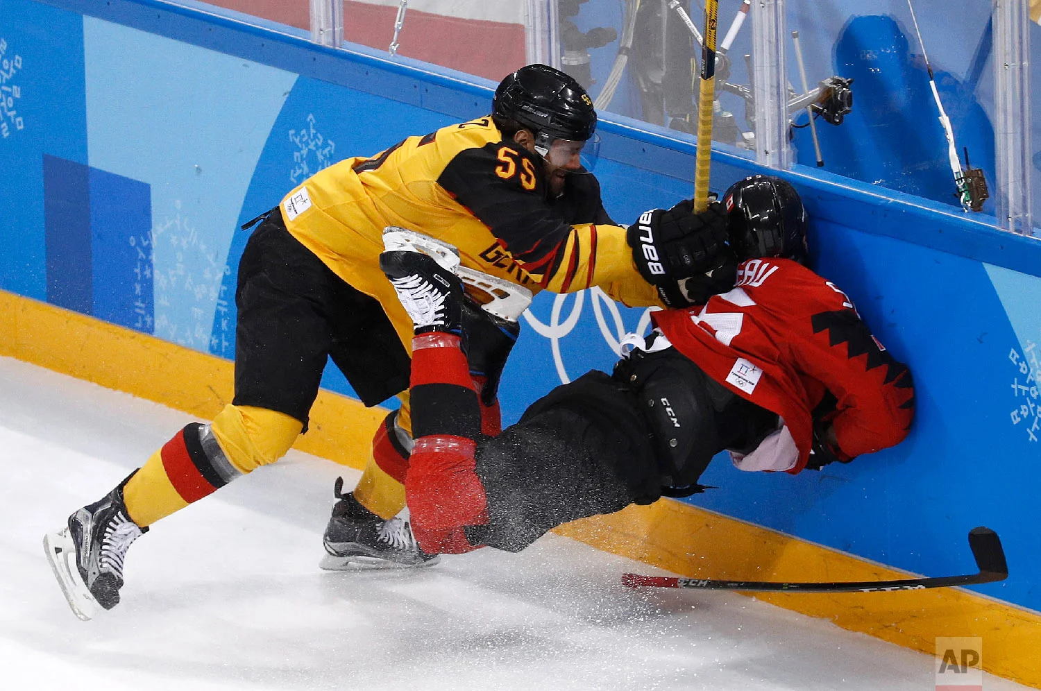 Felix Schutz (55), of Germany, slams Maxim Noreau (56), of Canada, into the wall during the first period of the semifinal round of the men's hockey game at the 2018 Winter Olympics in Gangneung, South Korea, Friday, Feb. 23, 2018. (AP Photo/Patrick Semansky)
