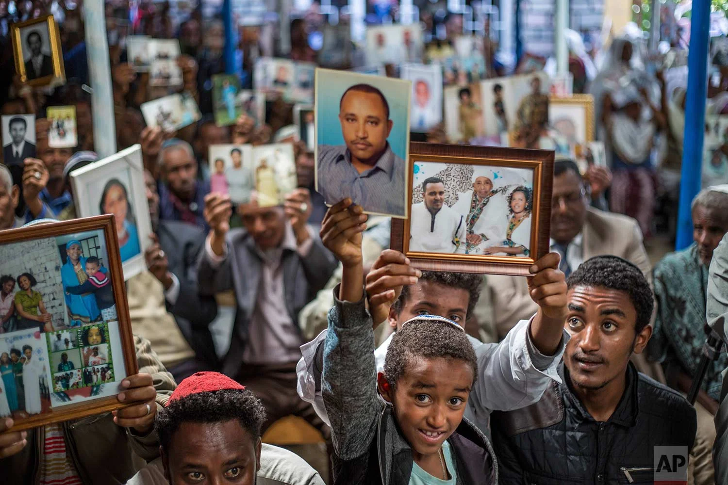 Members of Ethiopia's Jewish community hold pictures of their relatives in Israel, during a solidarity event at the synagogue in Addis Ababa, Ethiopia Wednesday, Feb. 28, 2018. (AP Photo/Mulugeta Ayene)