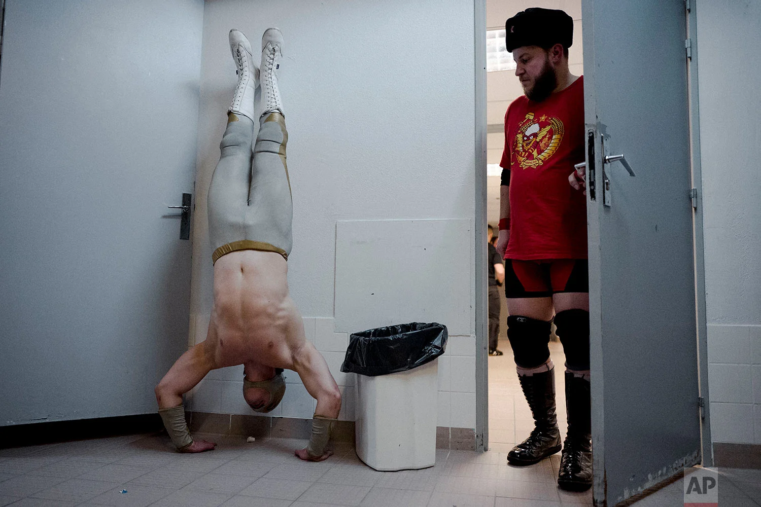  In this photo dated Saturday, Feb. 24, 2018, wrestler Ace Angel, left, warms up as rival wrestler PV Red looks on before taking part in a wrestling charity gala in Ivry-sur-Seine, south of Paris, France. (AP Photo/Kamil Zihnioglu) 