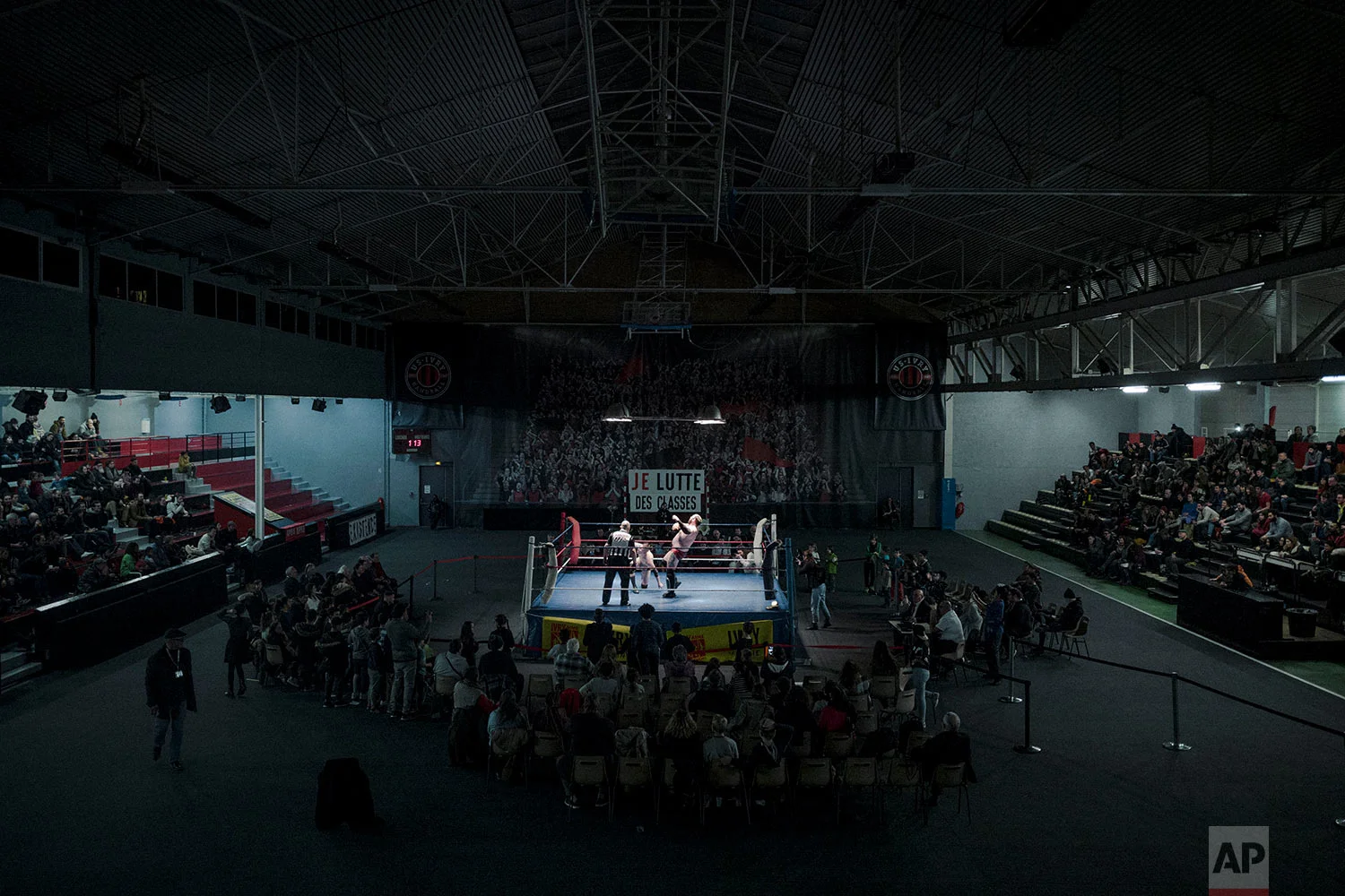  In this photo dated Saturday, Feb. 24, 2018, people watch wrestlers Darkmundo and Alex Legrand fighting during a wrestling charity gala in Ivry-sur-Seine, south of Paris, France. (AP Photo/Kamil Zihnioglu) 