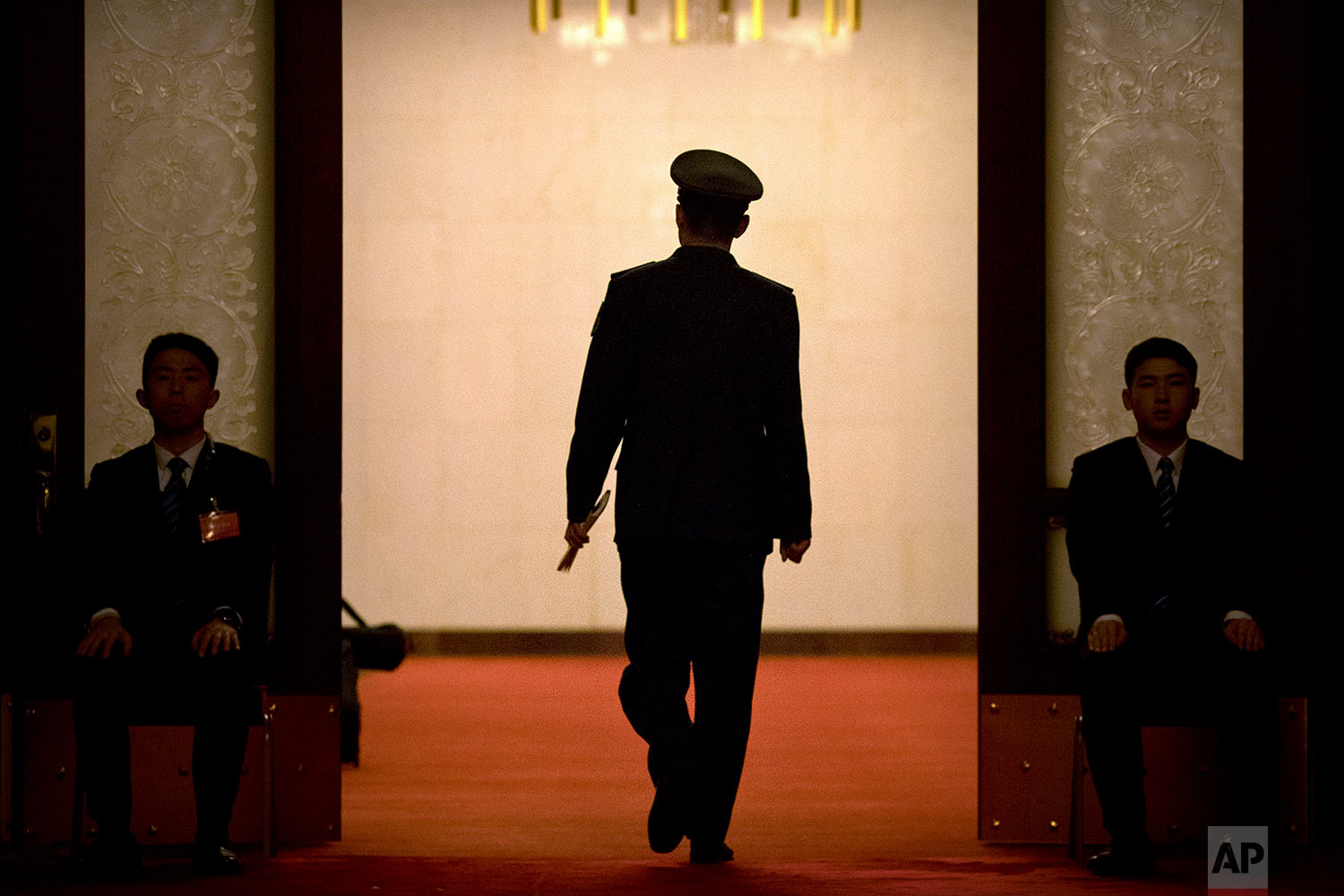  In this Friday, March 9, 2018 photo, a military officer walks through a door flanked by a pair of security officials during a plenary session of China's National People's Congress (NPC) at the Great Hall of the People in Beijing. (AP Photo/Mark Schi