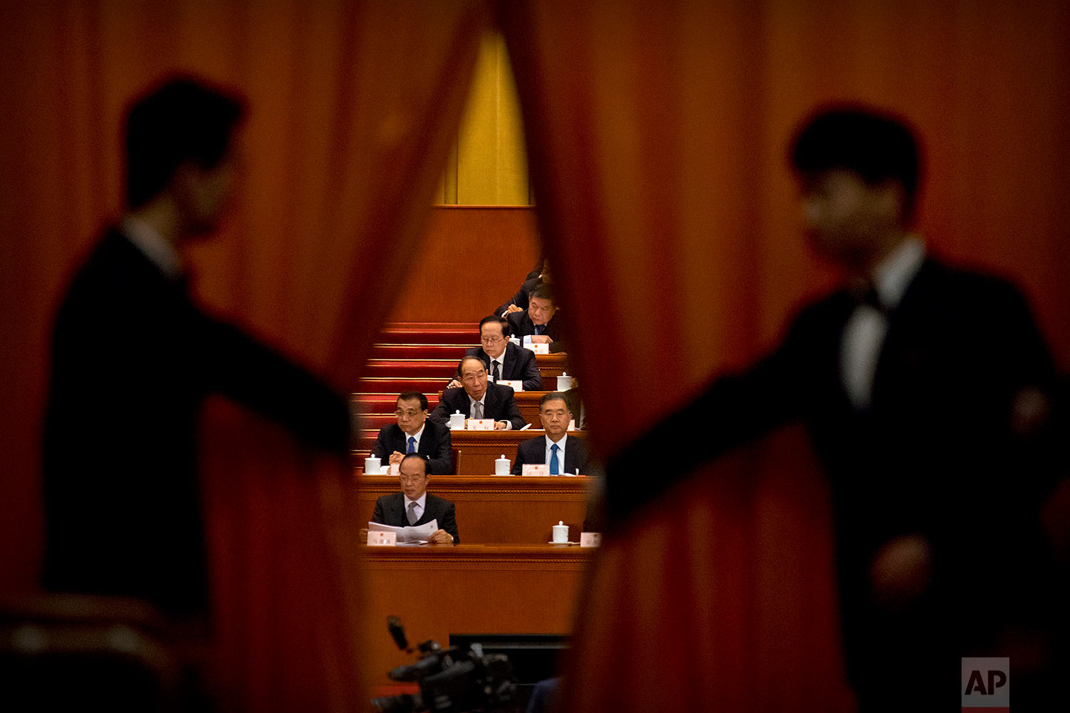  In this Friday, March 9, 2018 photo, ushers pull back a curtain as Chinese Premier Li Keqiang, second row left, and Politburo Standing Committee member Wang Yang, second row at right, attend a plenary session of China's National People's Congress (N