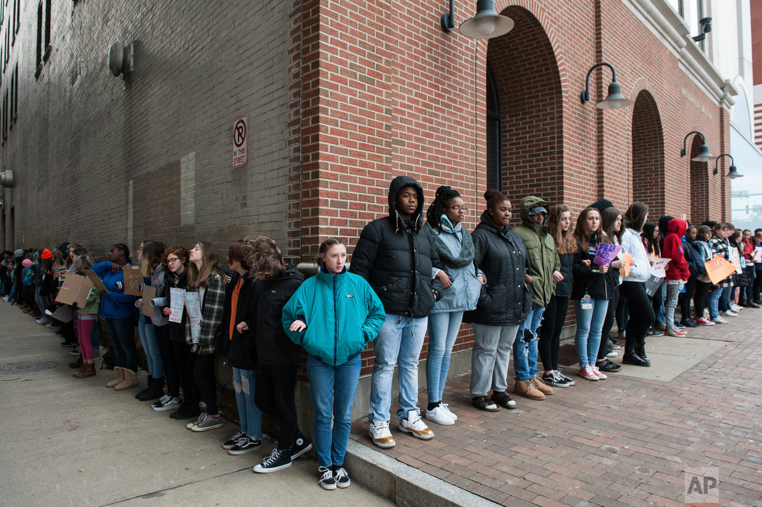 Lydia McGeehan, center, 16, joins fellow Pittsburgh Creative and Performing Arts School students to form a chain around their school in Pittsburgh on Wednesday, March 14, 2018, to mark the one month anniversary of the deadly shootings at Marjory Stoneman Douglas High School in Parkland, Fla. The students stood in silence for 17 minutes to mark the 17 students and faculty killed in the massacre. (Stephanie Strasburg/Pittsburgh Post-Gazette via AP)