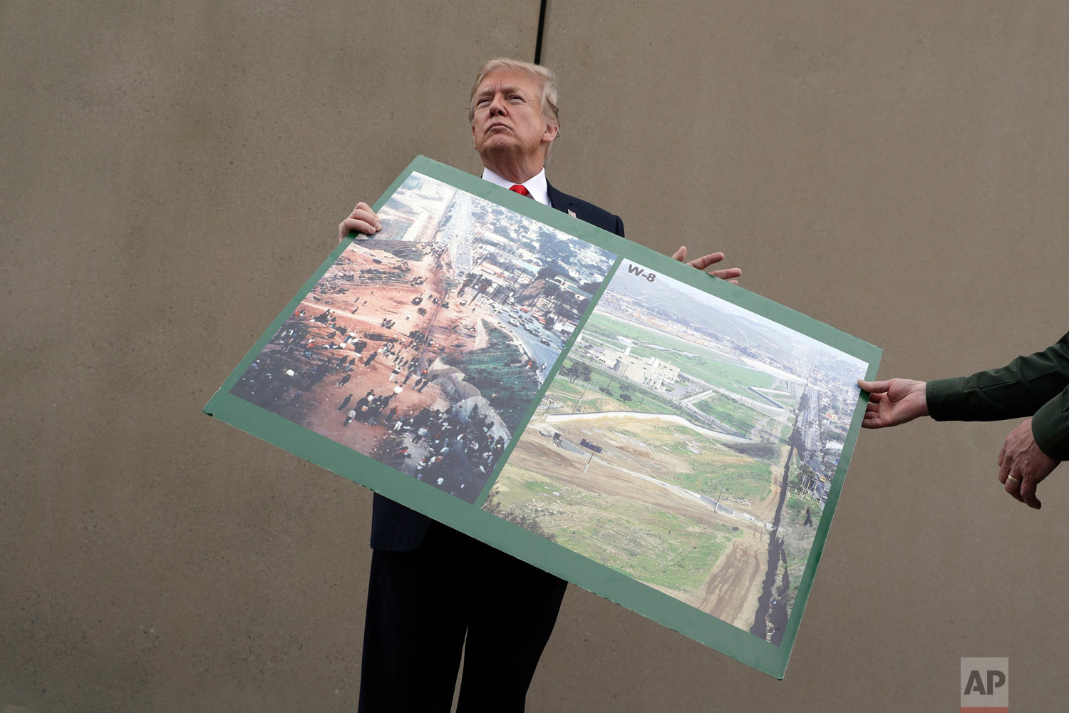  President Donald Trump holds a photo of the border area as he reviews border wall prototypes, Tuesday, March 13, 2018, in San Diego. Rodney Scott, the Border Patrol's San Diego sector chief, helps to hold the print. (AP Photo/Evan Vucci) 