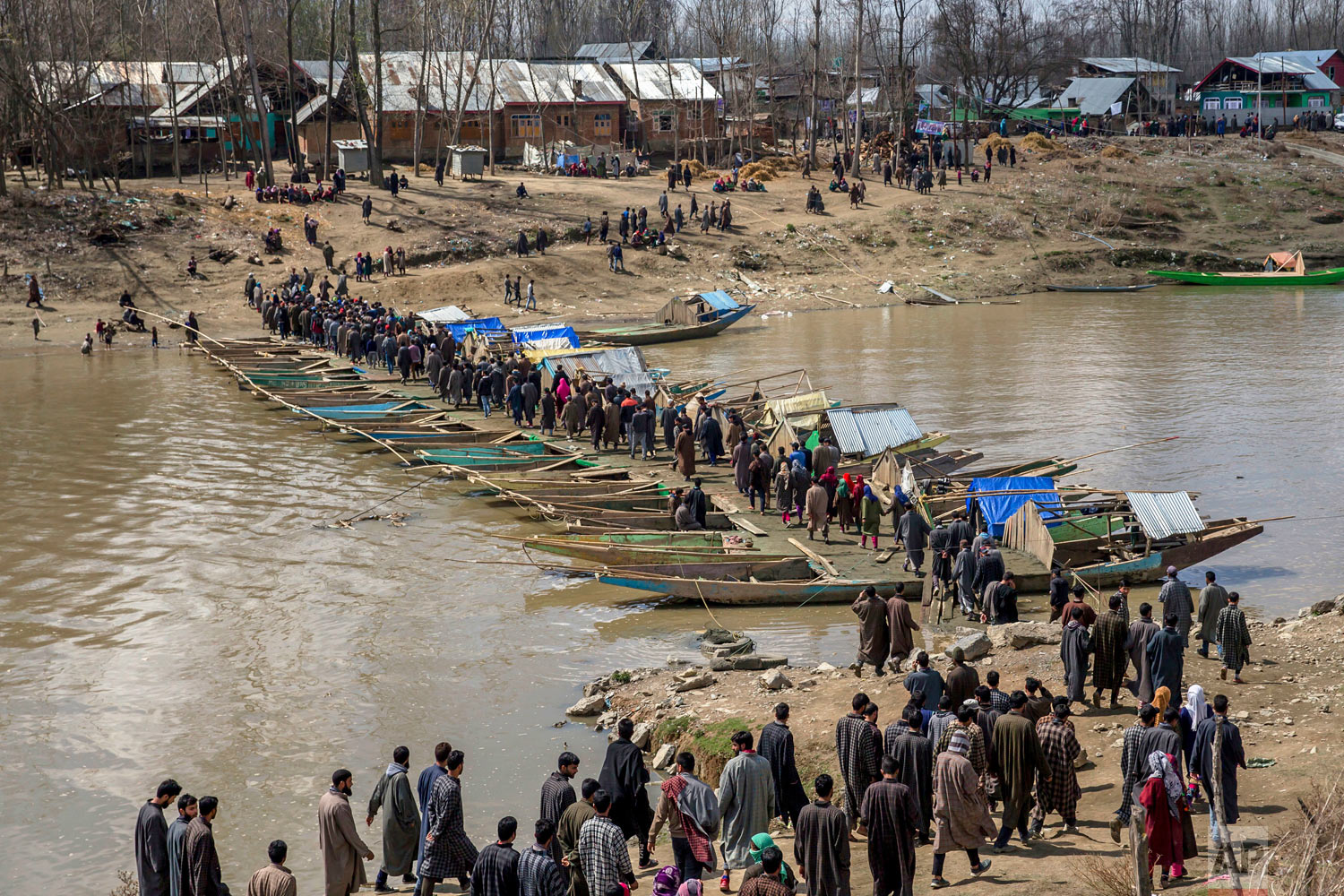  Kashmiri villagers walk on a temporary bridge made by lining up boats forming pathway across the river to attend the funeral of Shabir Ahmad, a suspected rebel, in Awantipora, 30 kilometrers (18 miles) south of Srinagar, Indian-controlled Kashmir, o