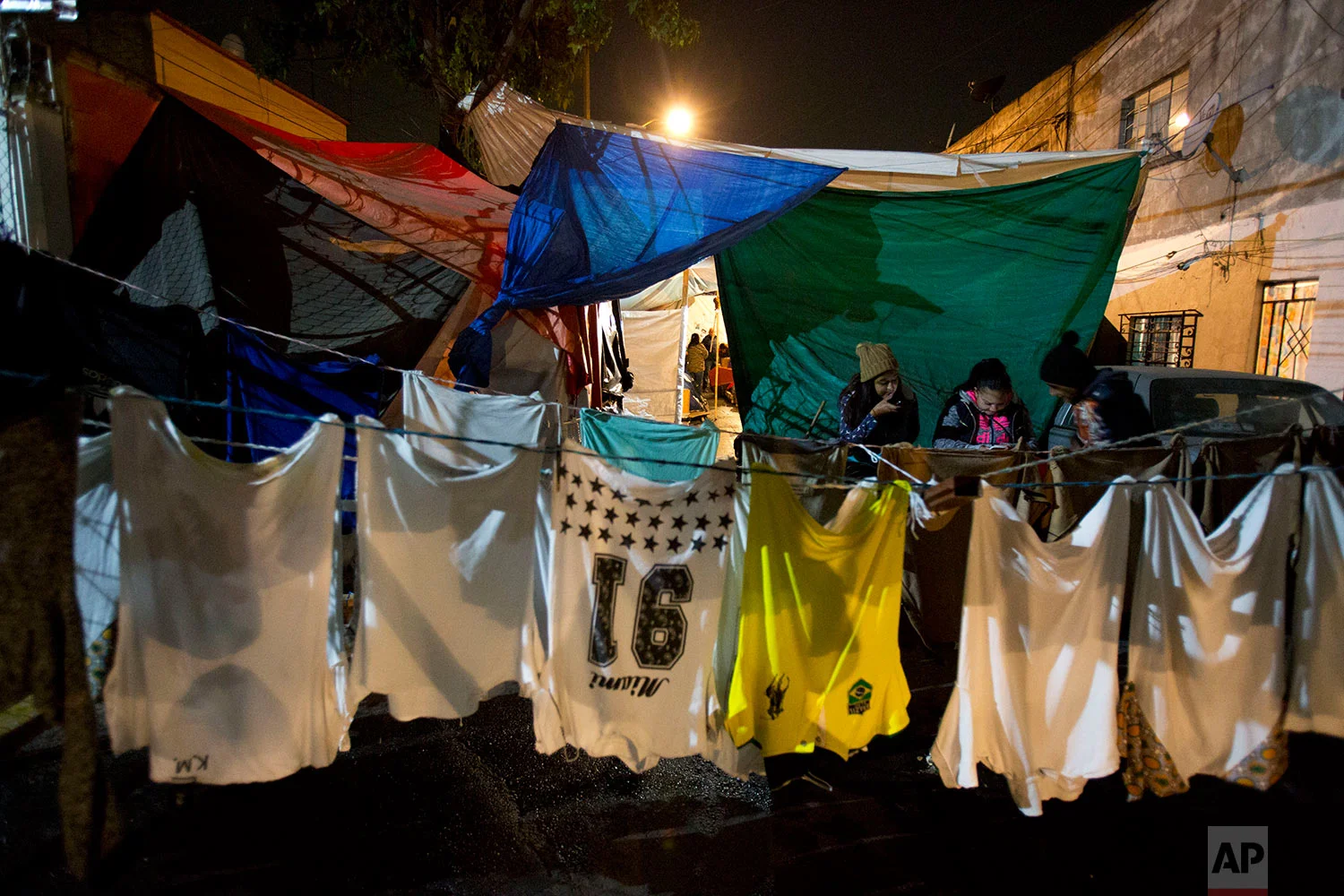  In this Jan. 12, 2018 photo, clothing hangs to dry in a tent camp where teenagers pass the time looking at a cell phone outside the earthquake-damaged Independencia 18 residence at night in Mexico City. (AP Photo/Rebecca Blackwell) 