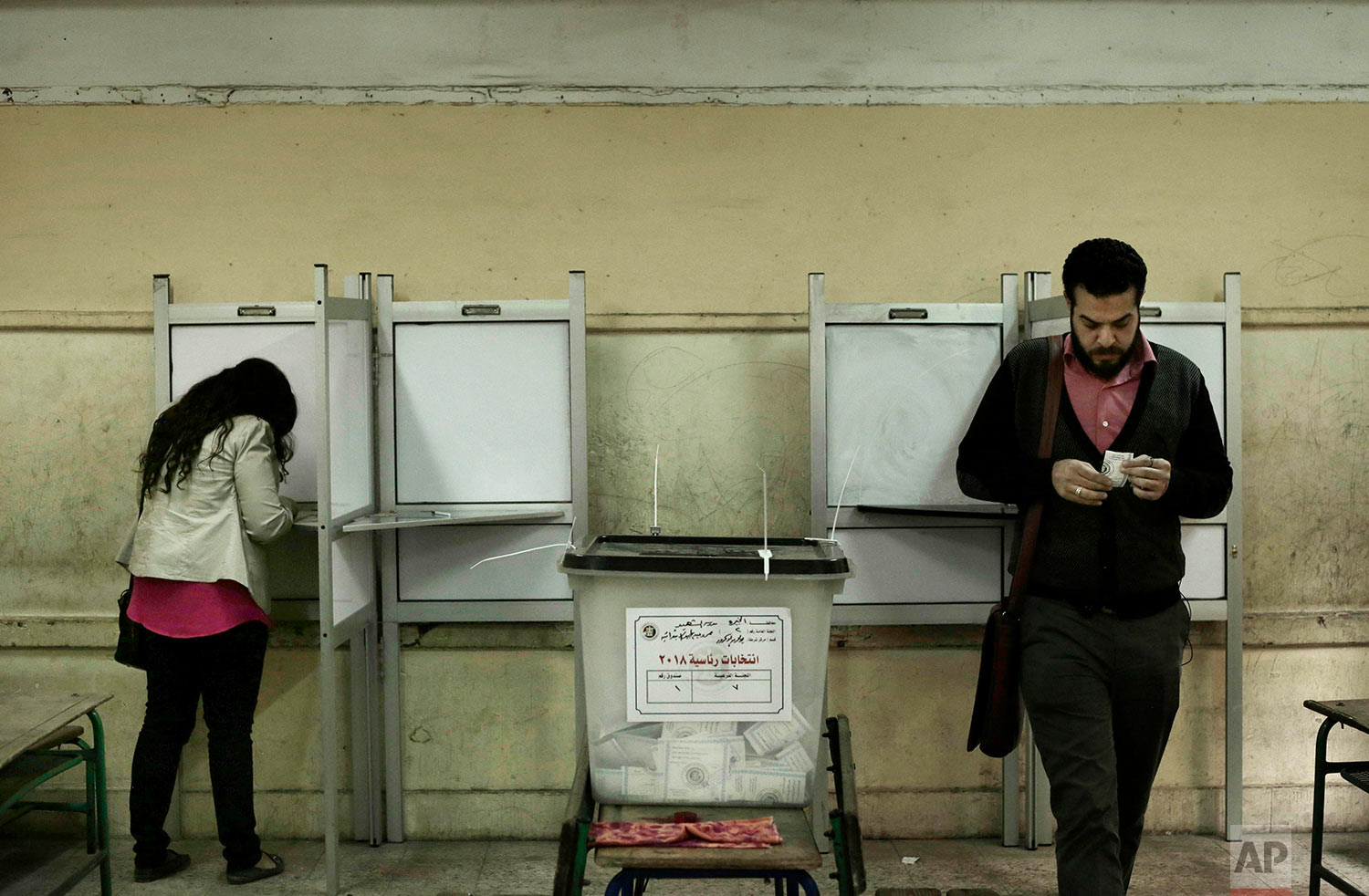 People vote inside polling station at a school in the Omraniyah district of Giza, Egypt Tuesday, March 27, 2018. Turnout appeared low as Egyptians voted on the second day of an election that President Abdel-Fattah el-Sissi is virtually certain to win, after all serious rivals were either arrested or intimidated into dropping out. (AP Photo/Nariman El-Mofty) 