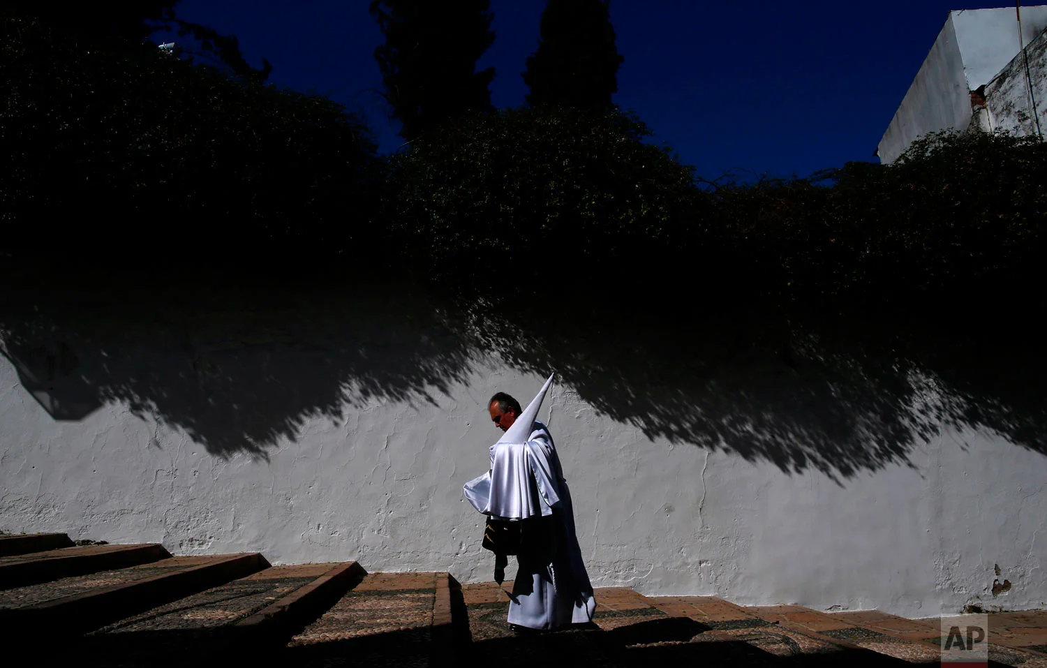 A penitent from the "La Paz" brotherhood walks to the church prior of the Holy Week procession in Cordoba, southern Spain, Wednesday, March 28, 2018. Hundreds of processions take place throughout Spain during the Easter Holy Week. (AP Photo/Manu Fer