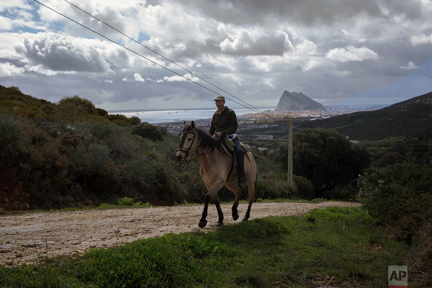 A man rides a horse backdropped by the Gibraltar's Rock and the town of La Linea de la Concepcion, in Cadiz province, south of Spain. (AP Photo/Emilio Morenatti)
