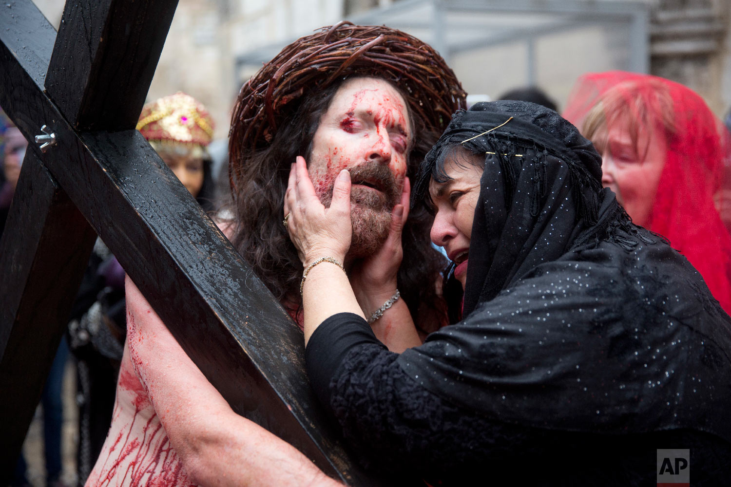 An actor dressed as Jesus Christ carries a cross as he reenacts the crucifixion walk along the Via Dolorosa towards the Church of the Holy Sepulchre, traditionally believed by many to be the site of the crucifixion of Jesus Christ, during the Good Friday procession in Jerusalem's Old City in Jerusalem, Friday, March 30, 2018. (AP Photo/Ariel Schalit)